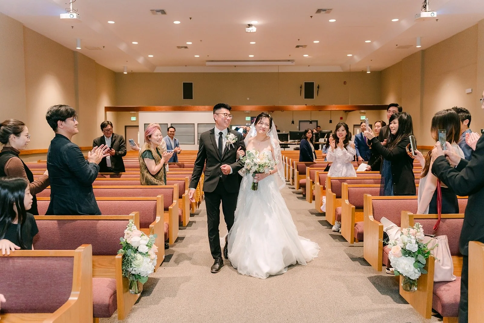 Guests clap as Eunice and Eric leave the sanctuary at Mandarin Baptist Church of Los Angeles, photographed by One and Only Production