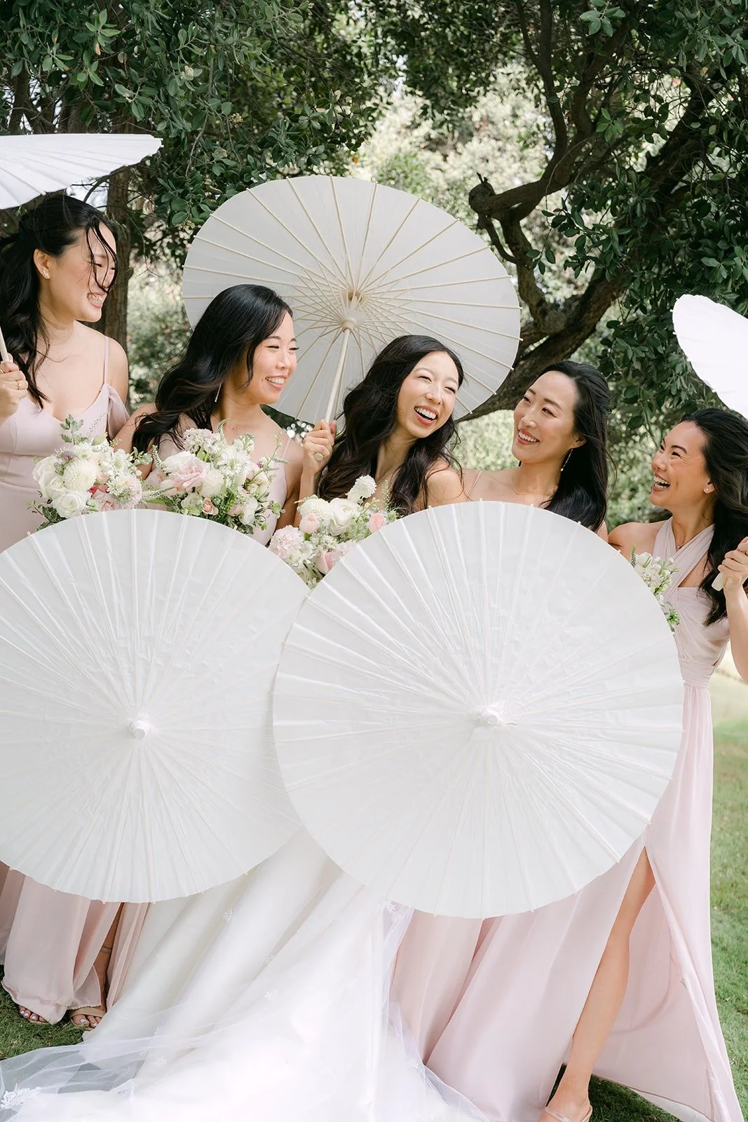 Kristine and her bridesmaids posing with white paper parasols