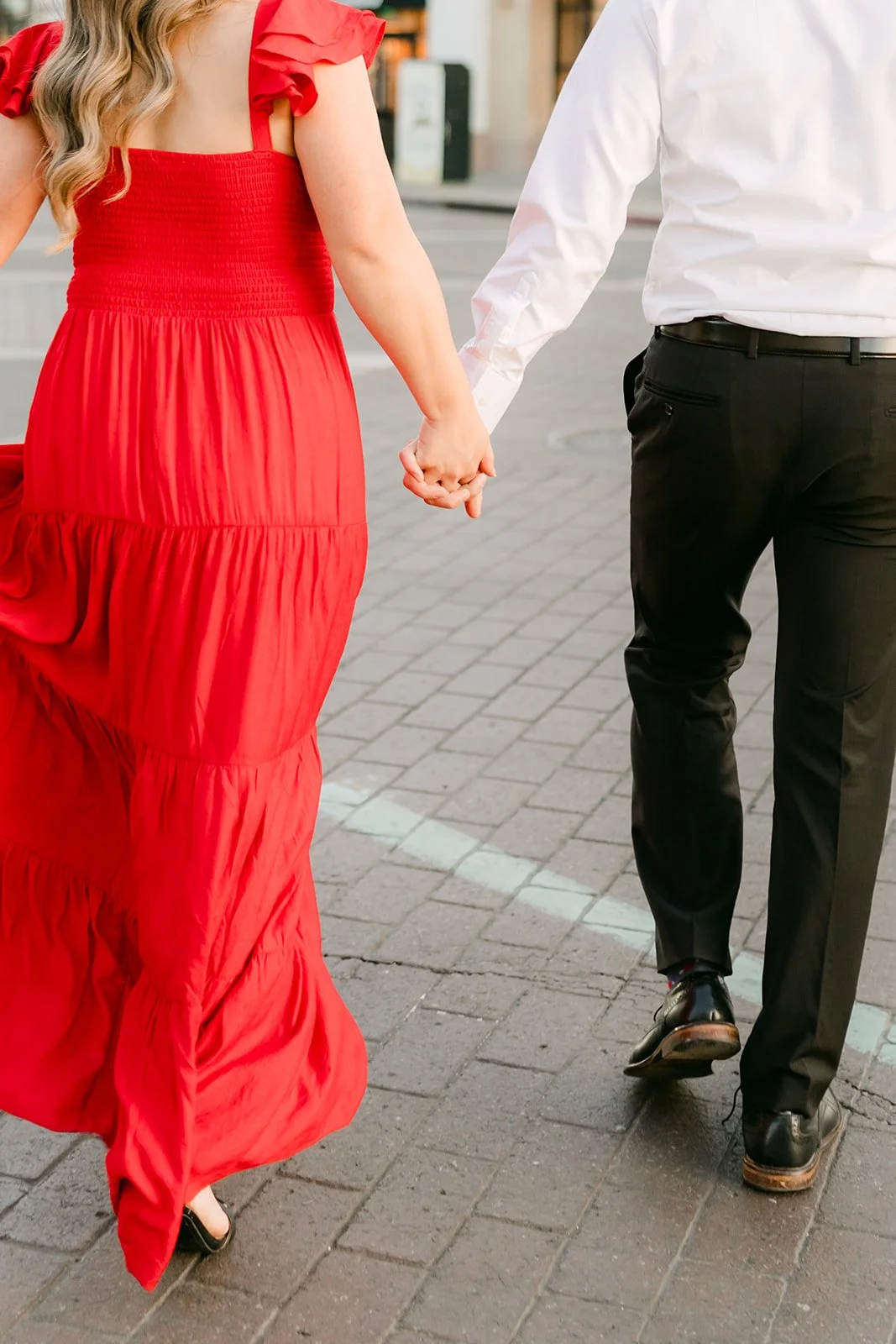 Close-up of Linh leading Ankush by the hand across the street.