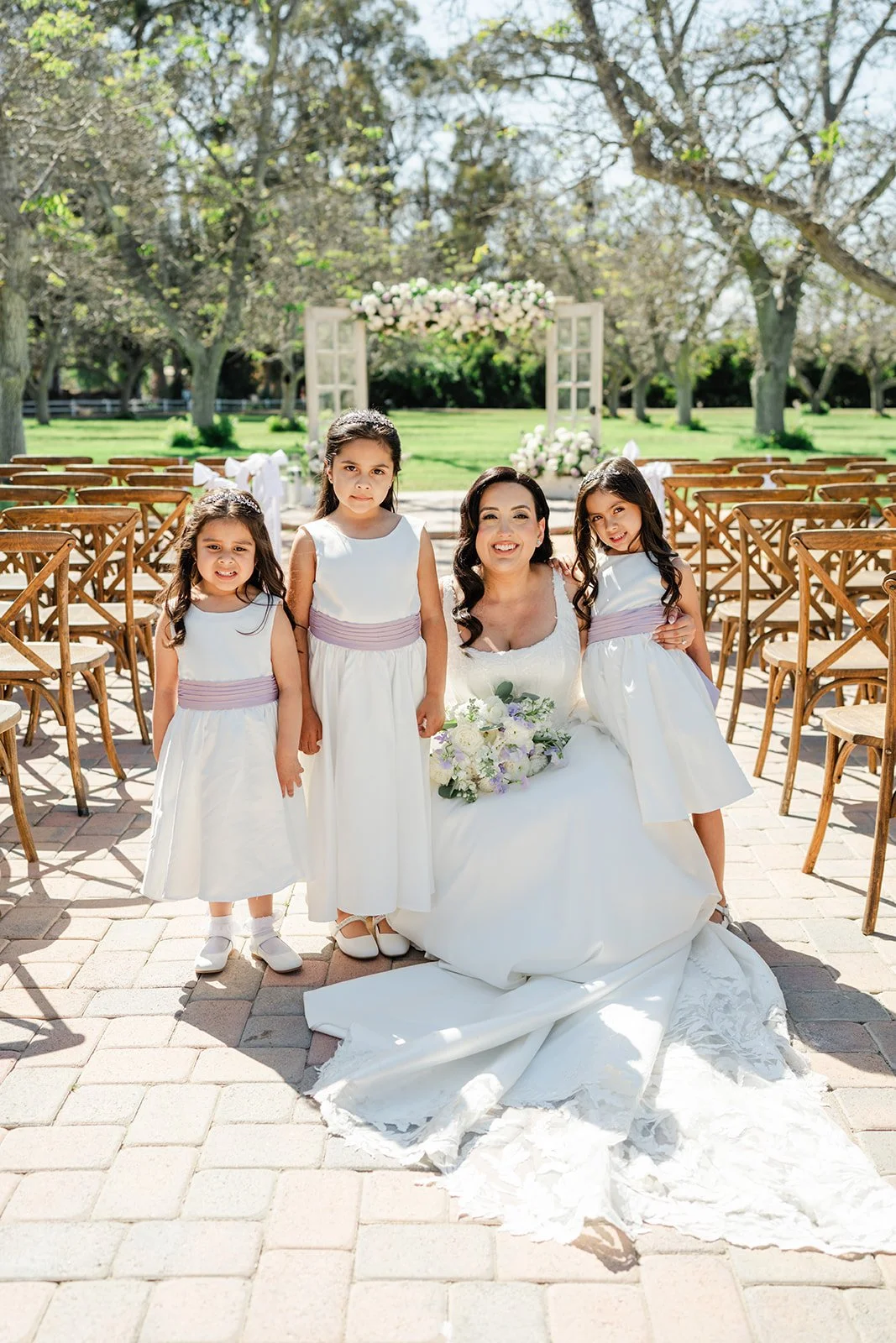 Bride with her flower girls in white dresses with lavender sashes