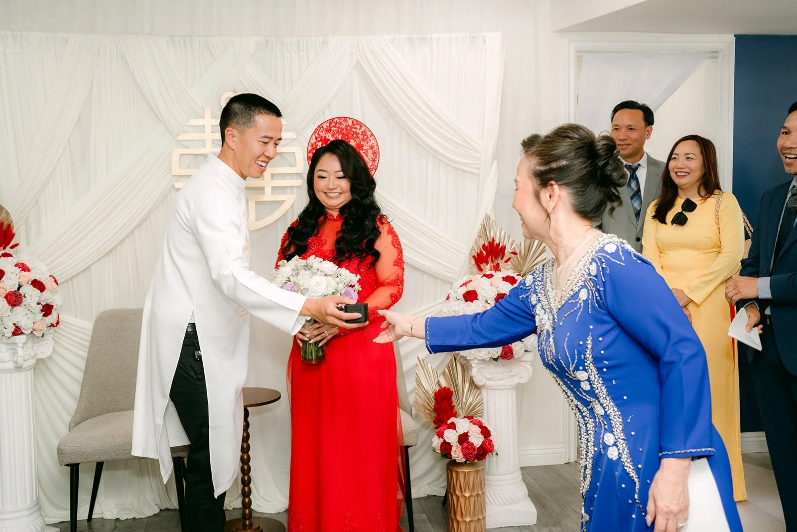 A family member in a blue ao dai greets Jennifer and Kevin during the tea ceremony
