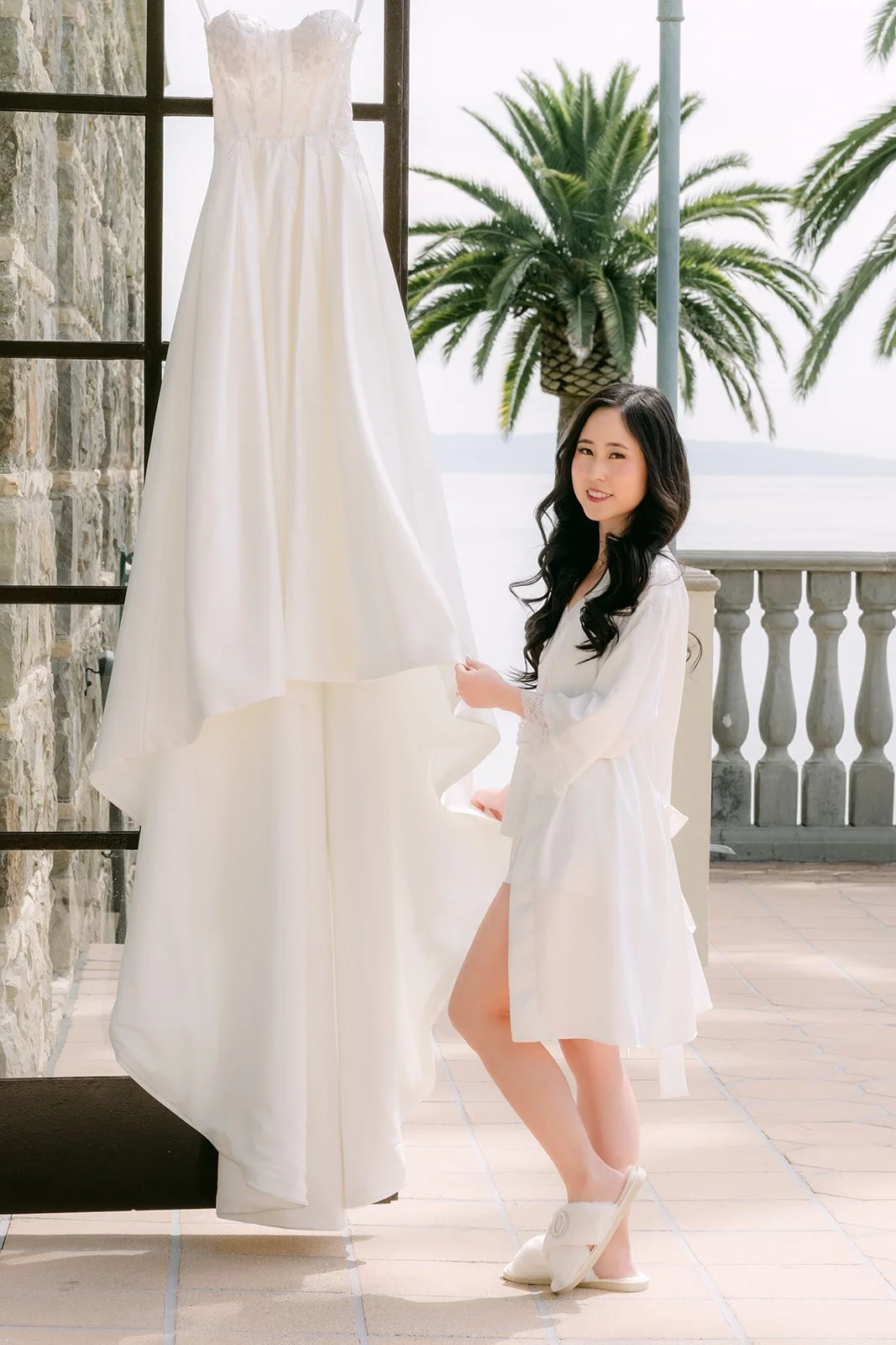 Kelley standing beside her wedding gown by the window