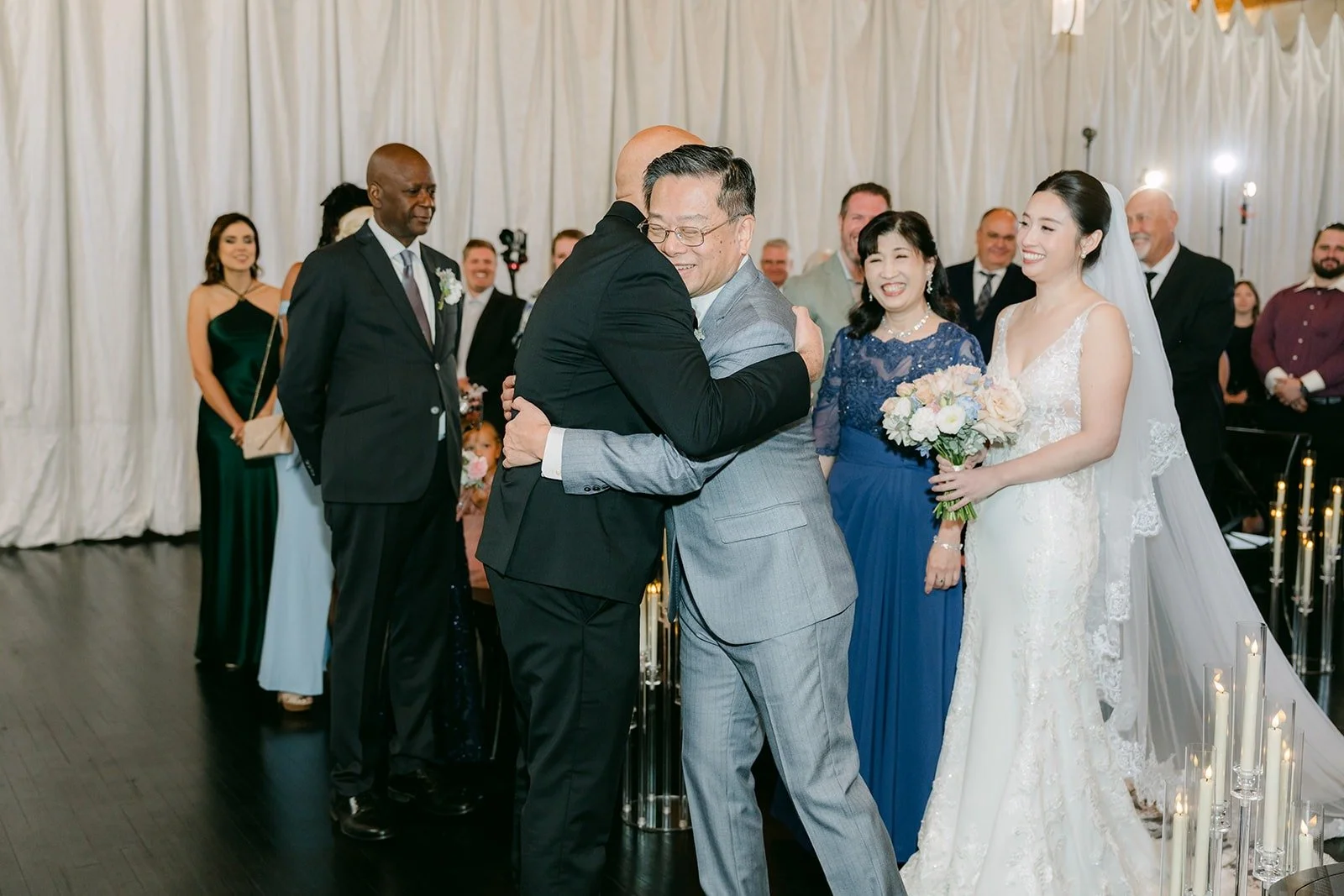 A family member hugs Brandon at the end of the aisle