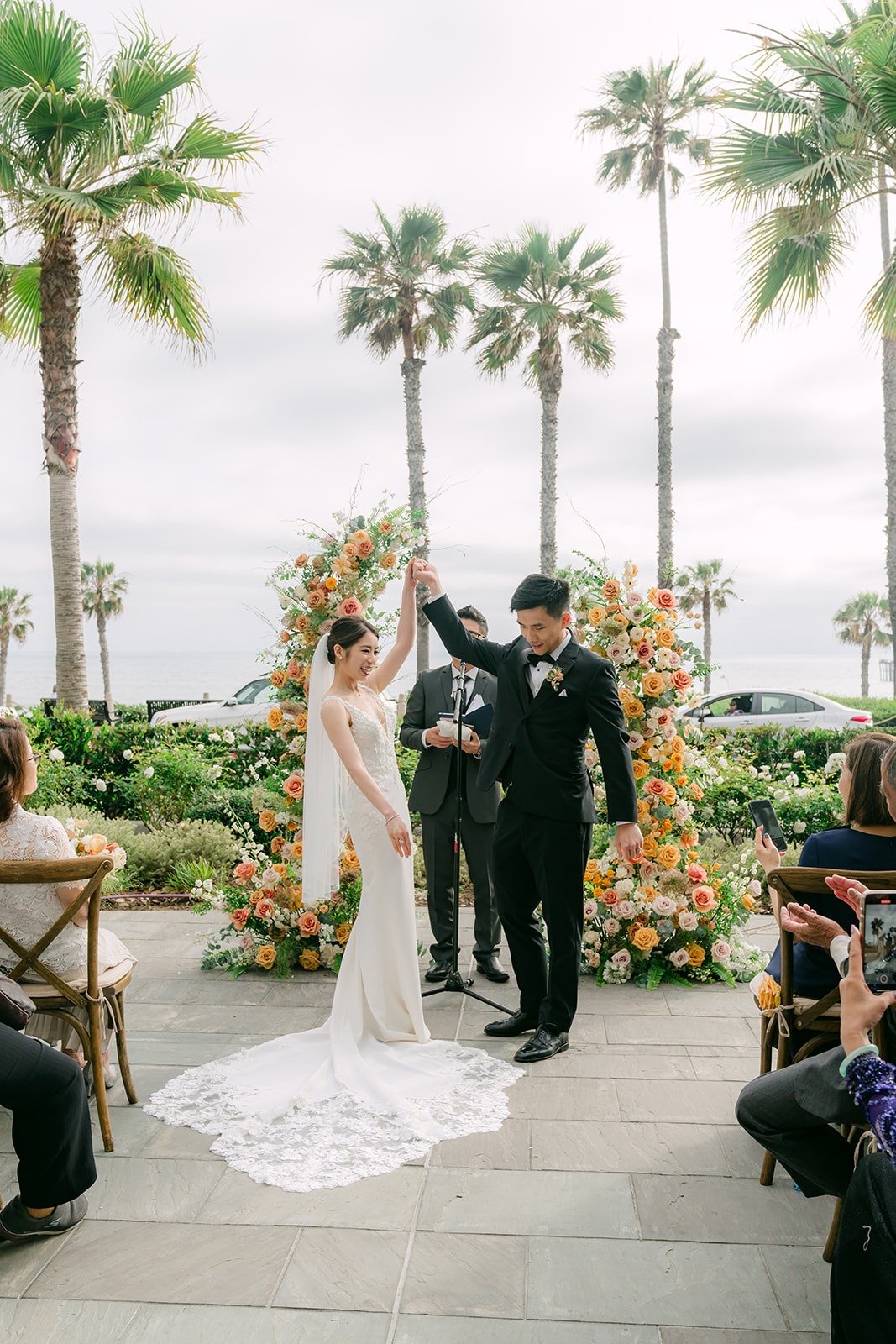 Angela and Eli kissing at the end of the aisle as guests cheer