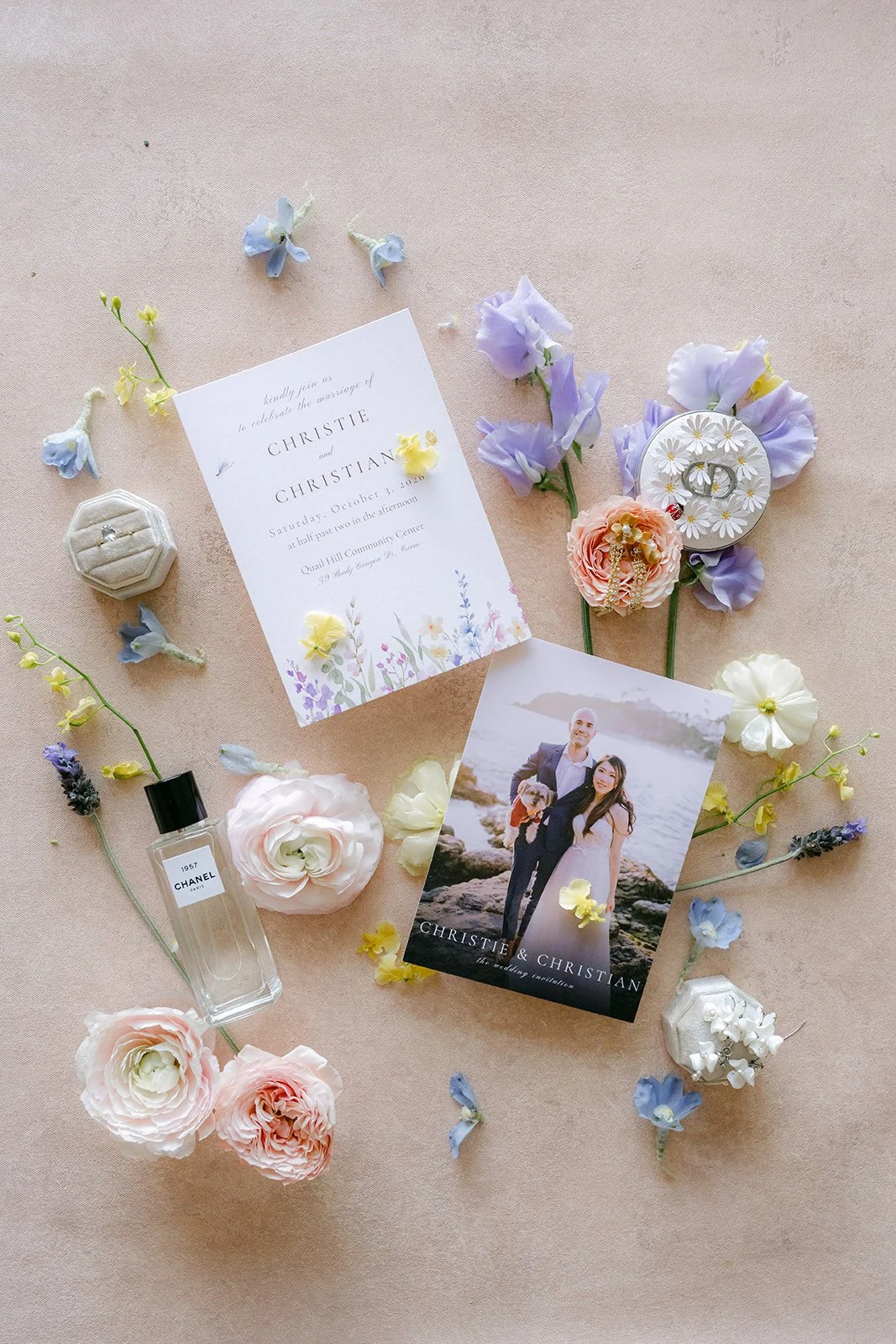 Christie's wedding details styled with a lilac invitation suite, perfume, rings and pastel florals.
