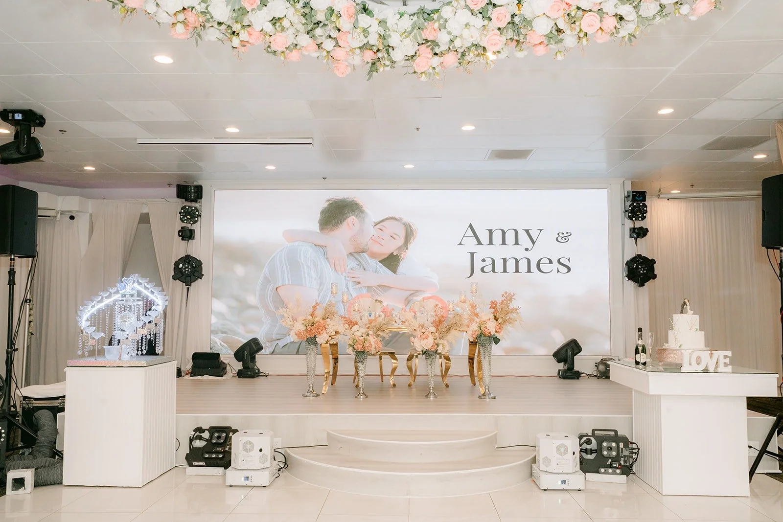 Head table and stage with ivory drapery and floral chandelier