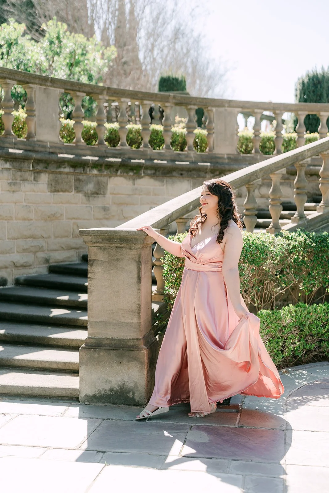 Saira lifting her blush gown on the curved stone staircase.
