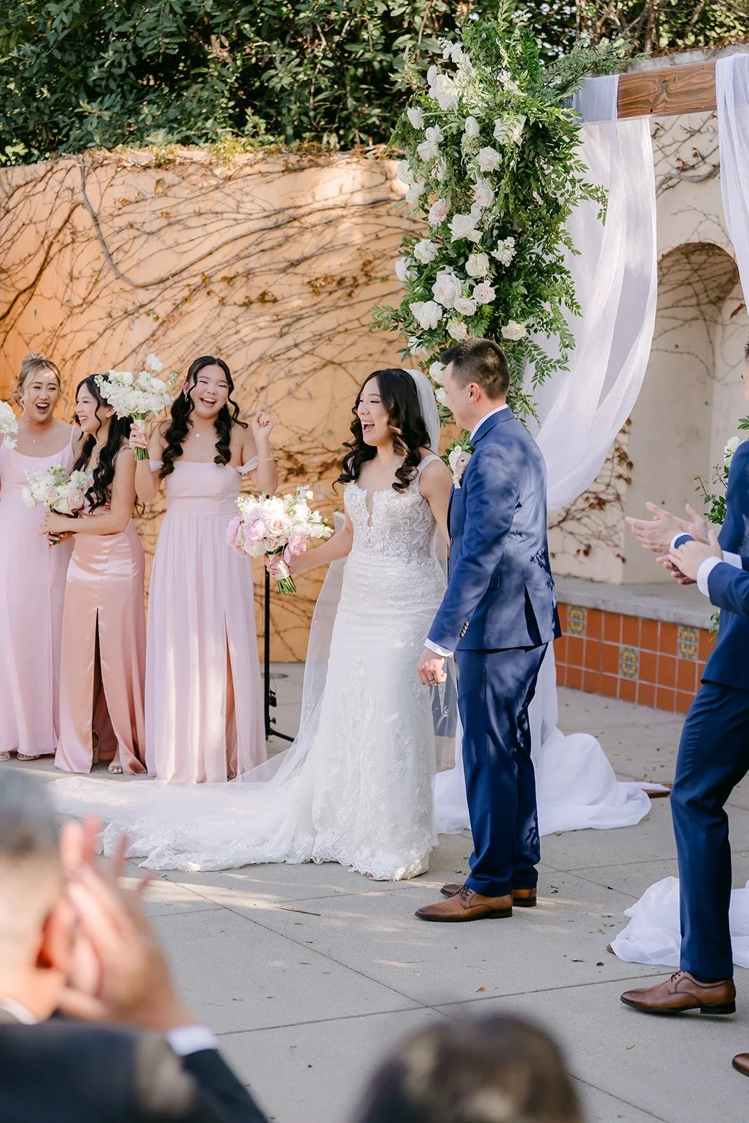 Kelli and Alex at the arch with the bridesmaids standing beside them