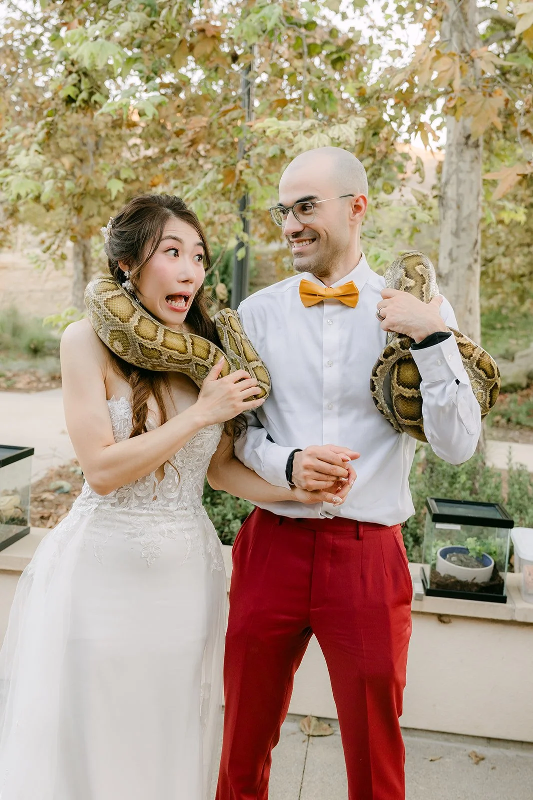 Christie with a snake around her shoulders while Christian laughs beside her.