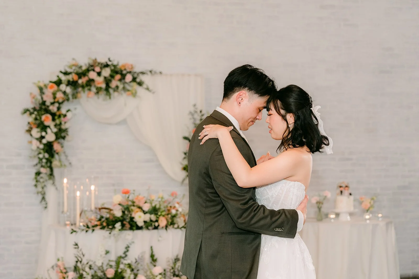 Couple slow dancing in front of the floral arch