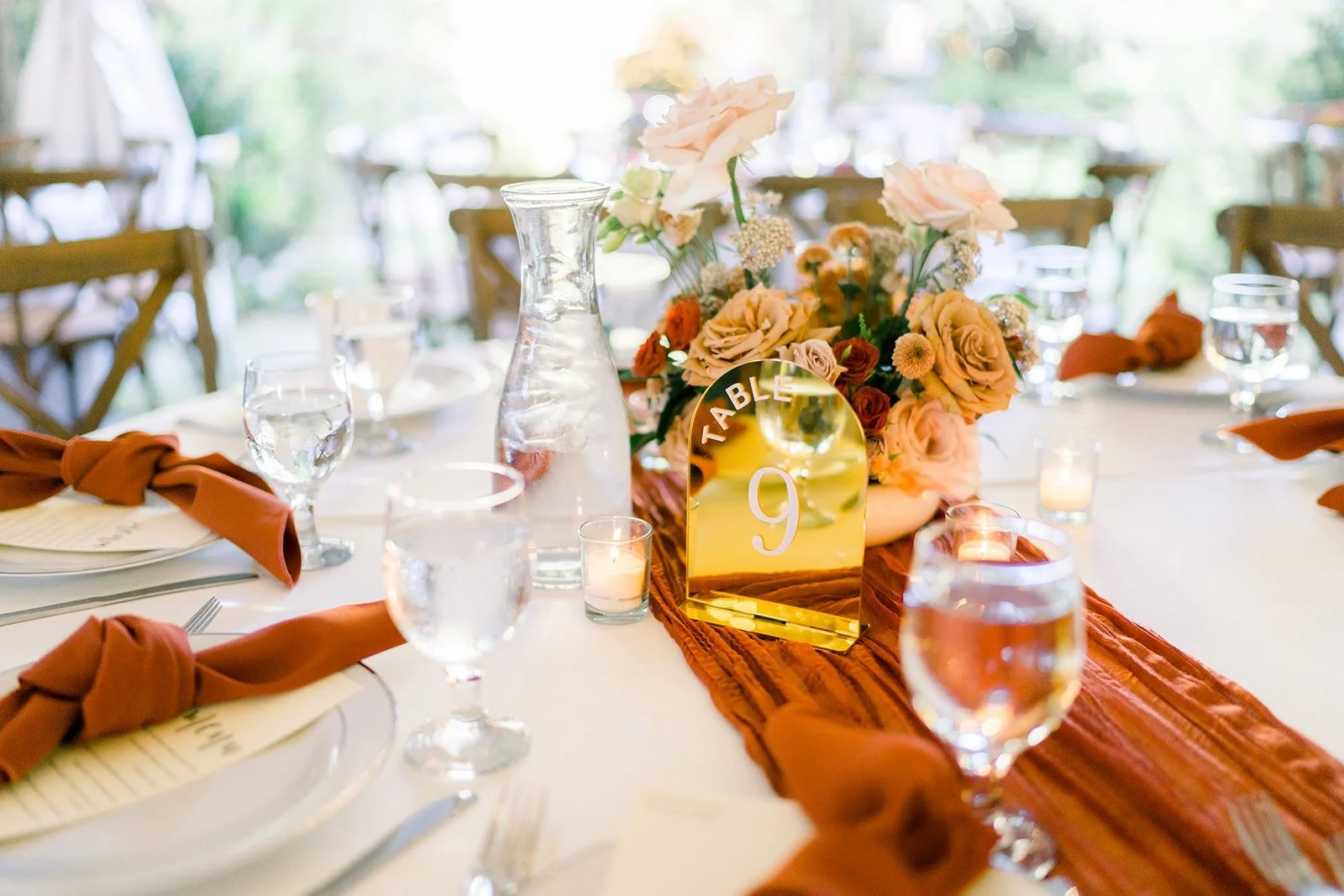 Long wooden table set with rust runners and greenery