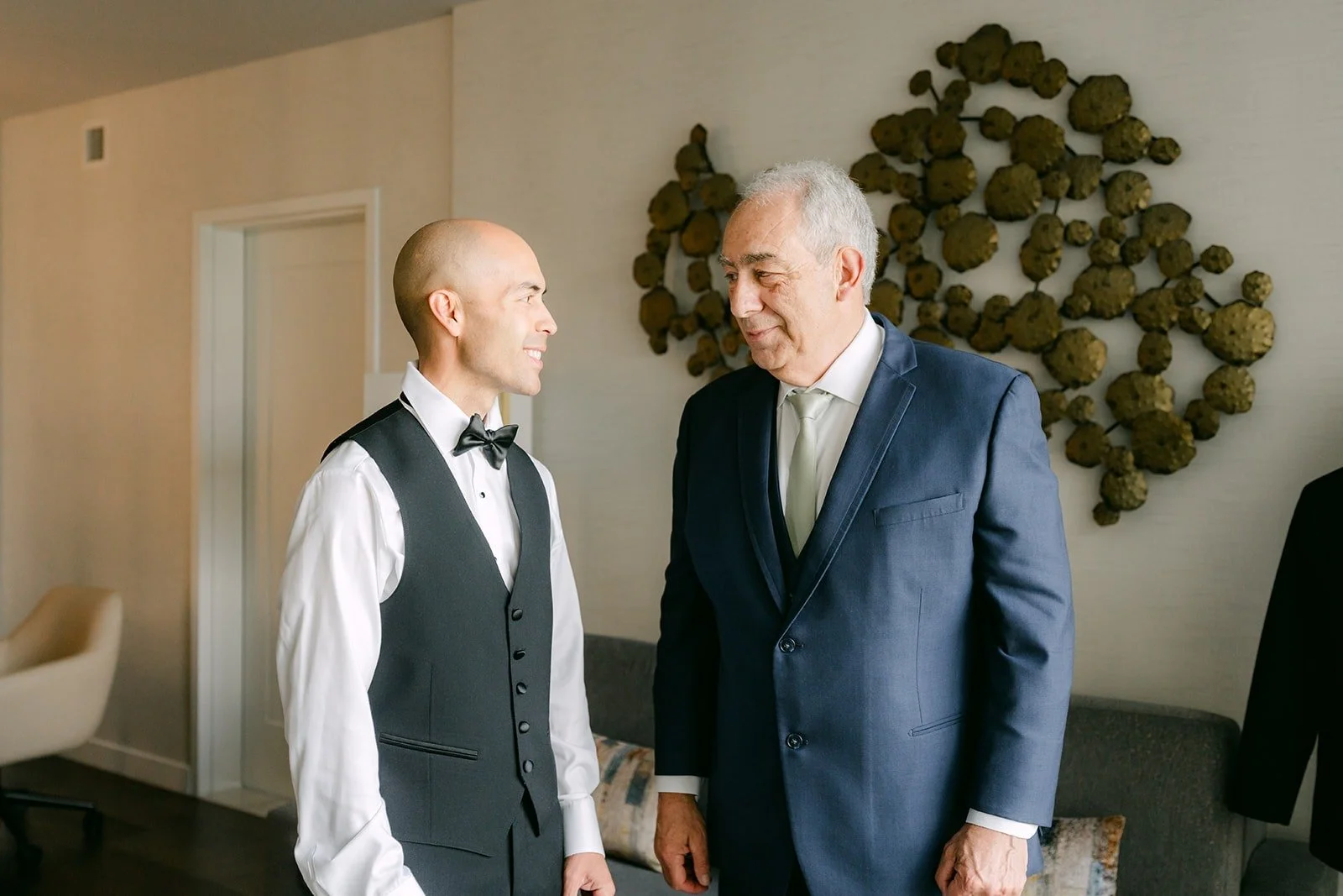 Daniel in his vest talks with a family member in the Groom Suite