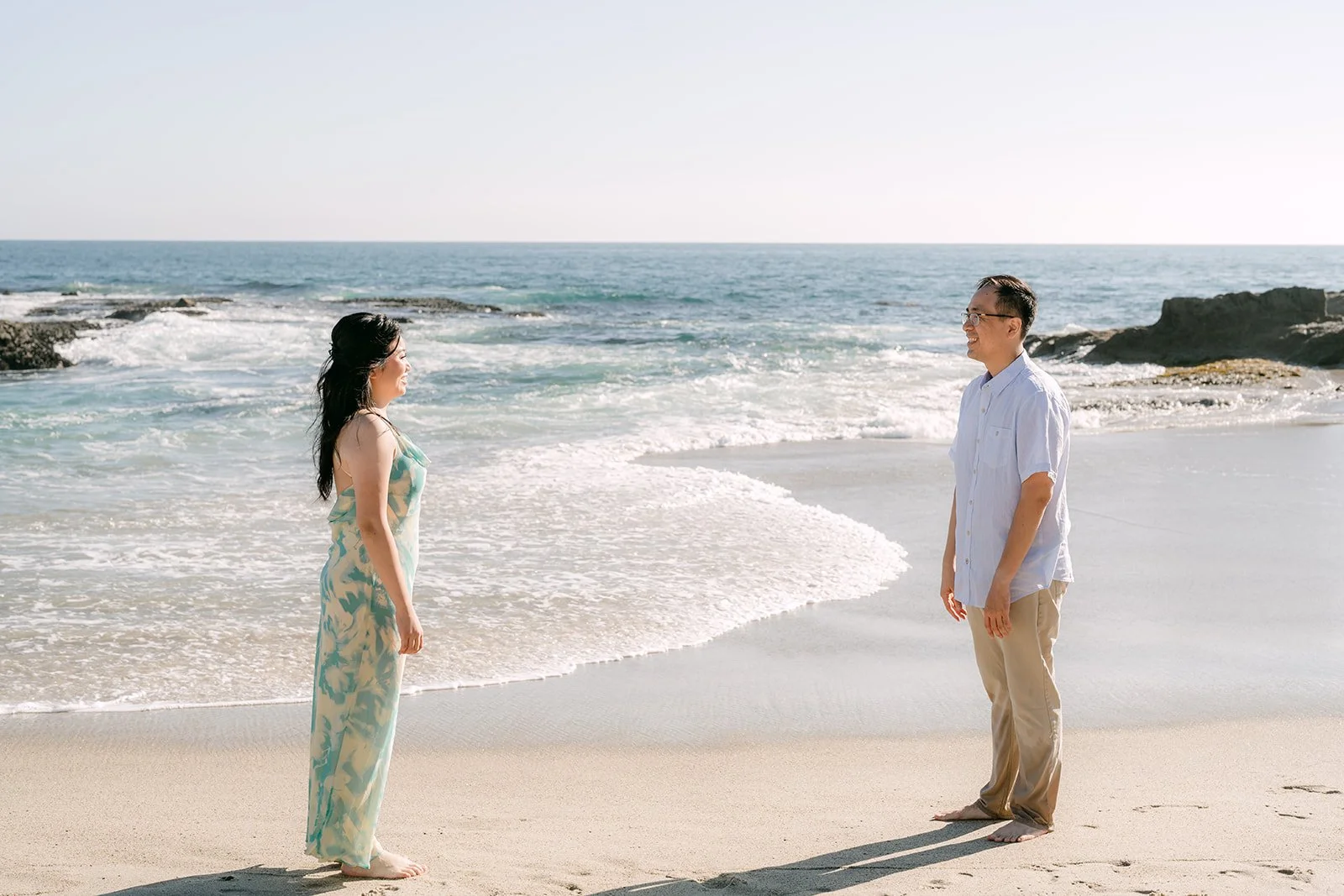 Constance and Lawrence facing each other by the ocean.