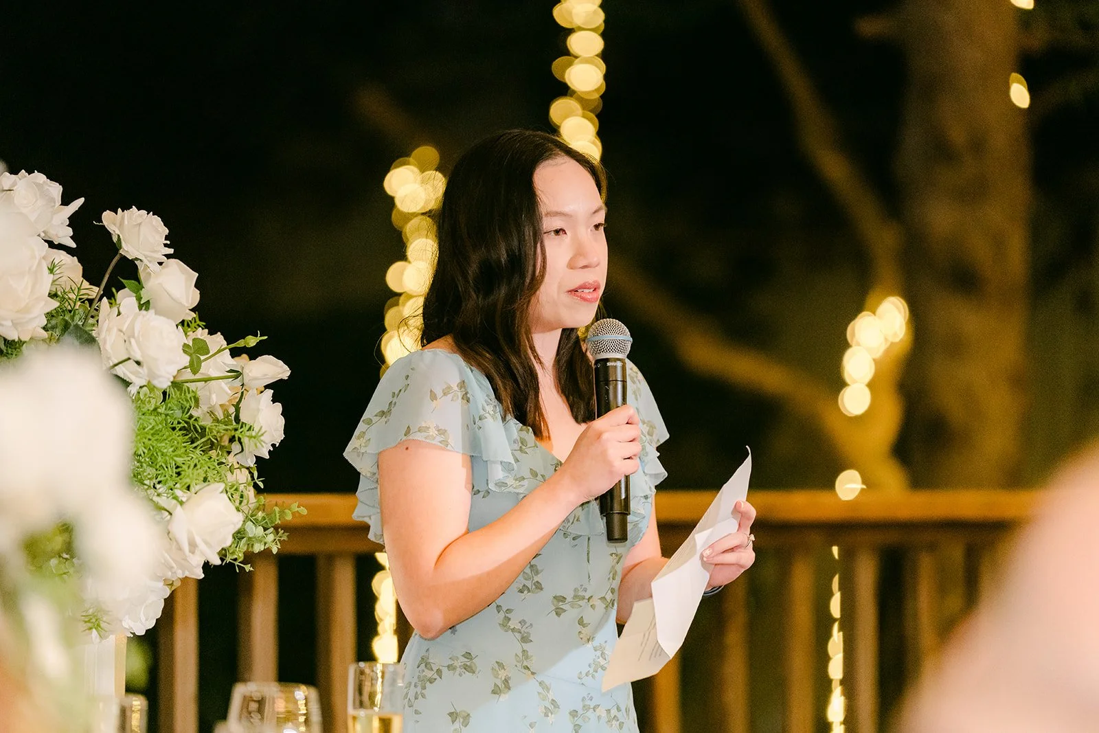 Bridesmaid in a blue floral dress giving her speech