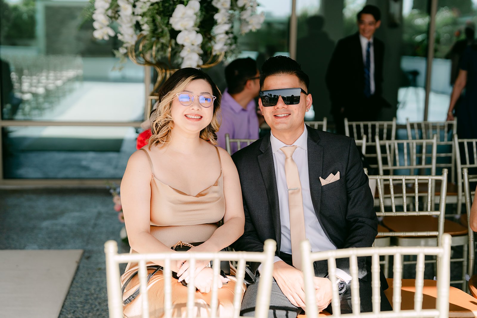 Guests in sunglasses smiling during the ceremony.