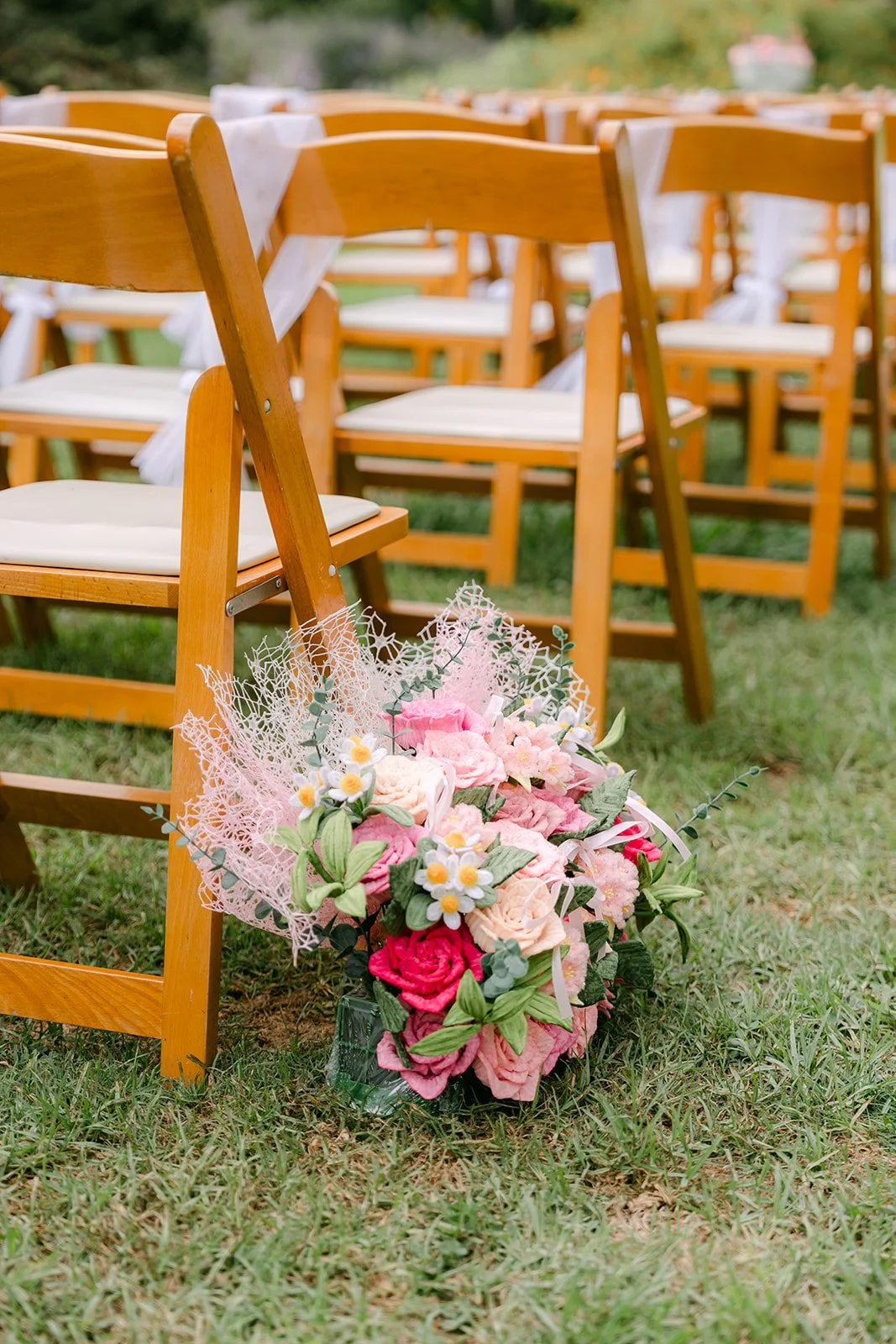 Pink and white aisle florals beside a wooden chair.