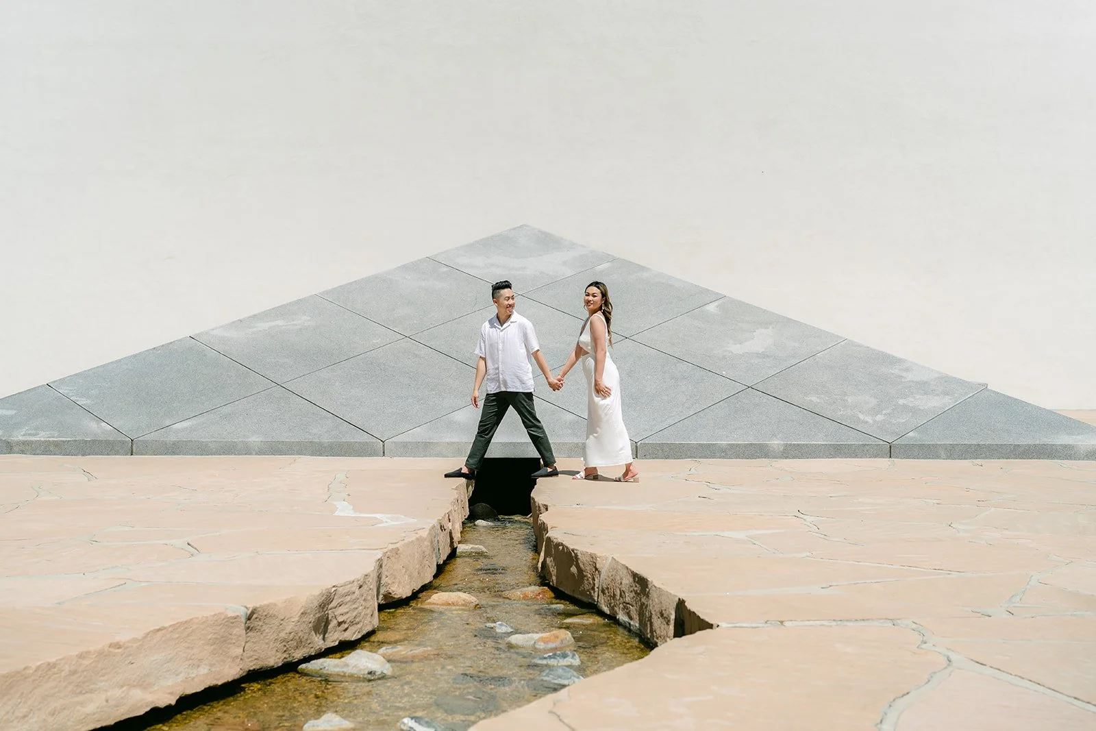 Stephanie and Alan lean in for a kiss across the stream in front of the granite pyramid.