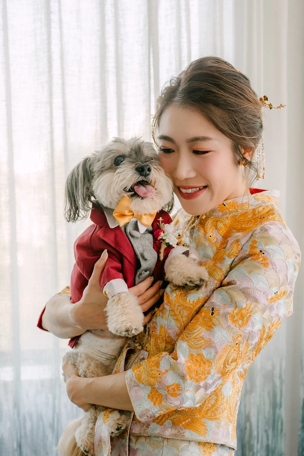 Christie holding her dog Izzo, dressed in a red outfit for the wedding.