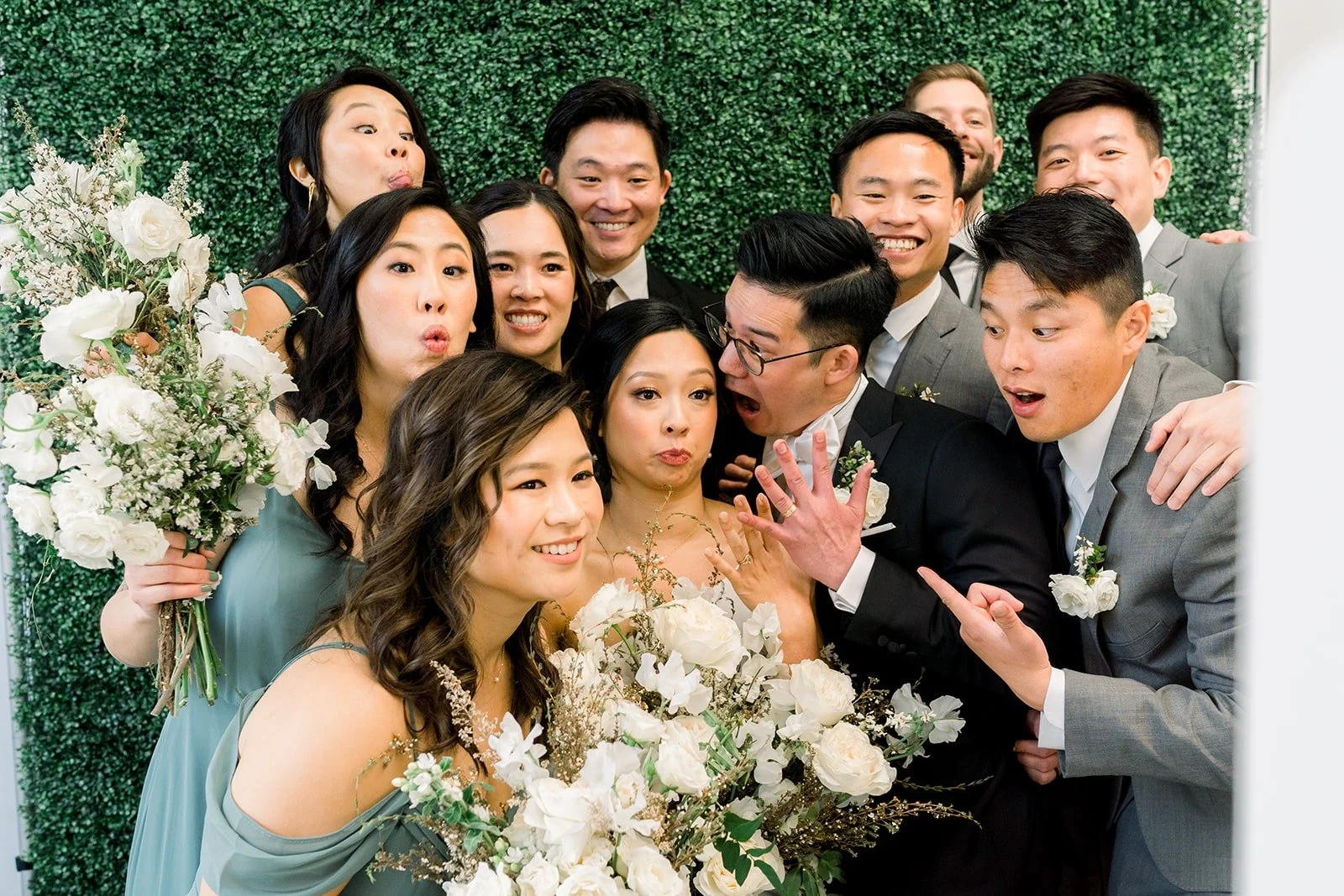 The wedding party crowds in close and laughing, photographed by One and Only Production