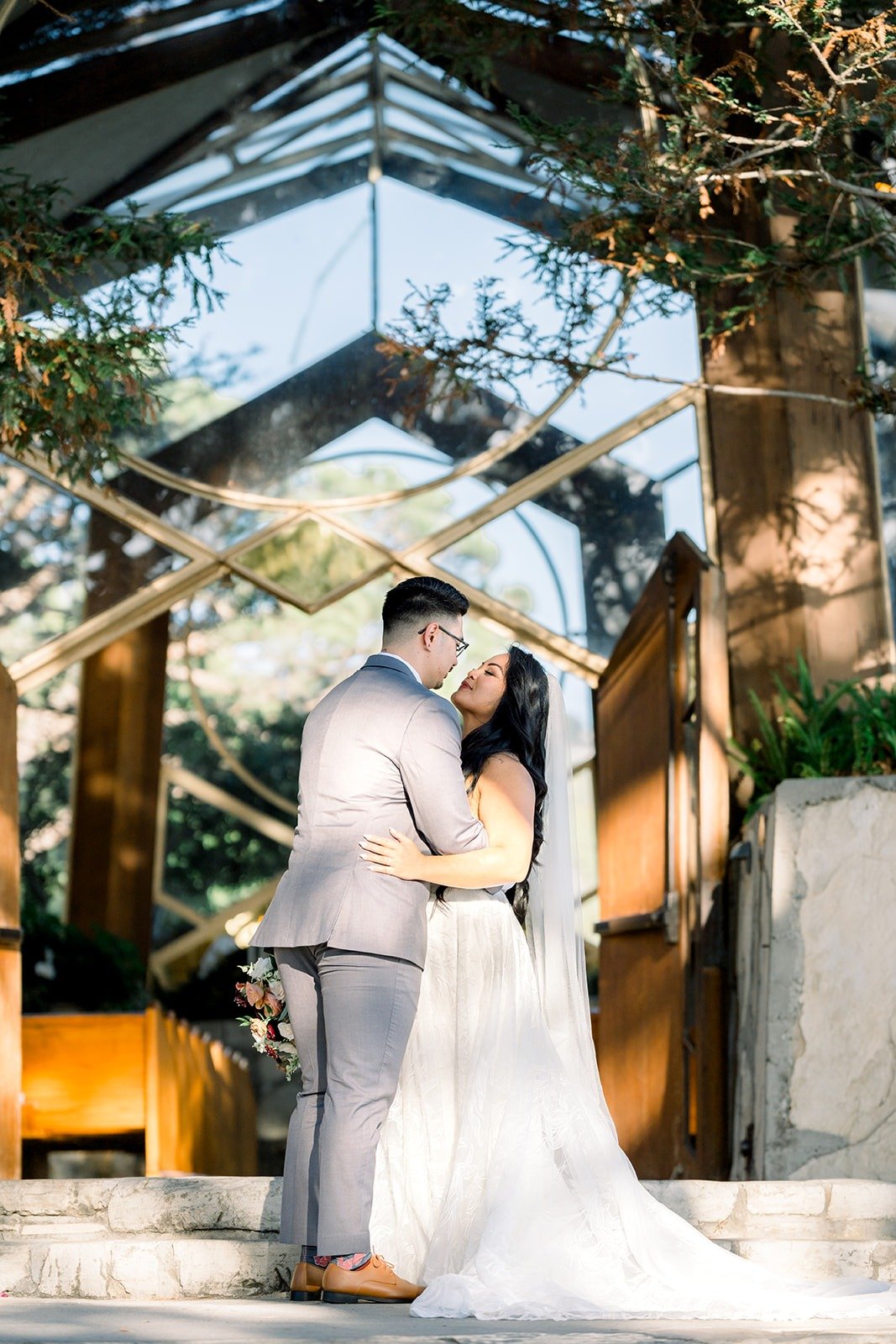Betsy and Mikey kiss under the glass roof of Wayfarers Chapel