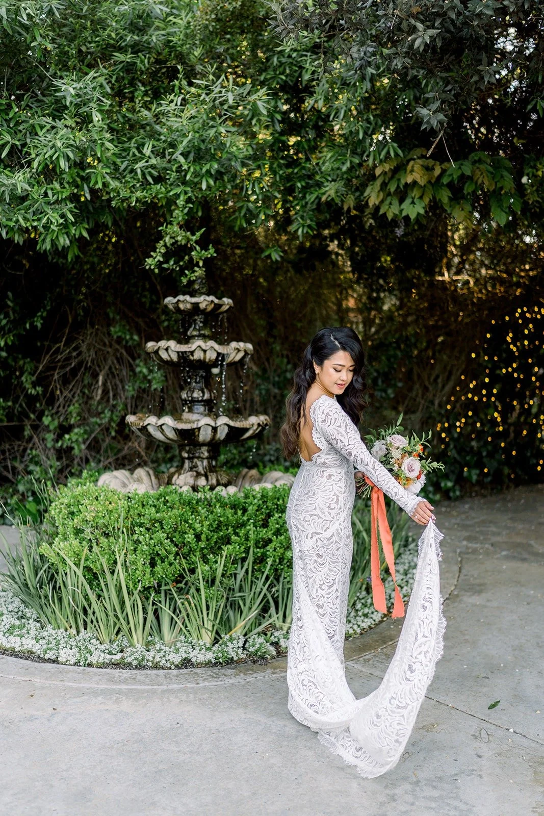 Hannah by the garden fountain with her long veil trailing, photographed by One and Only Production