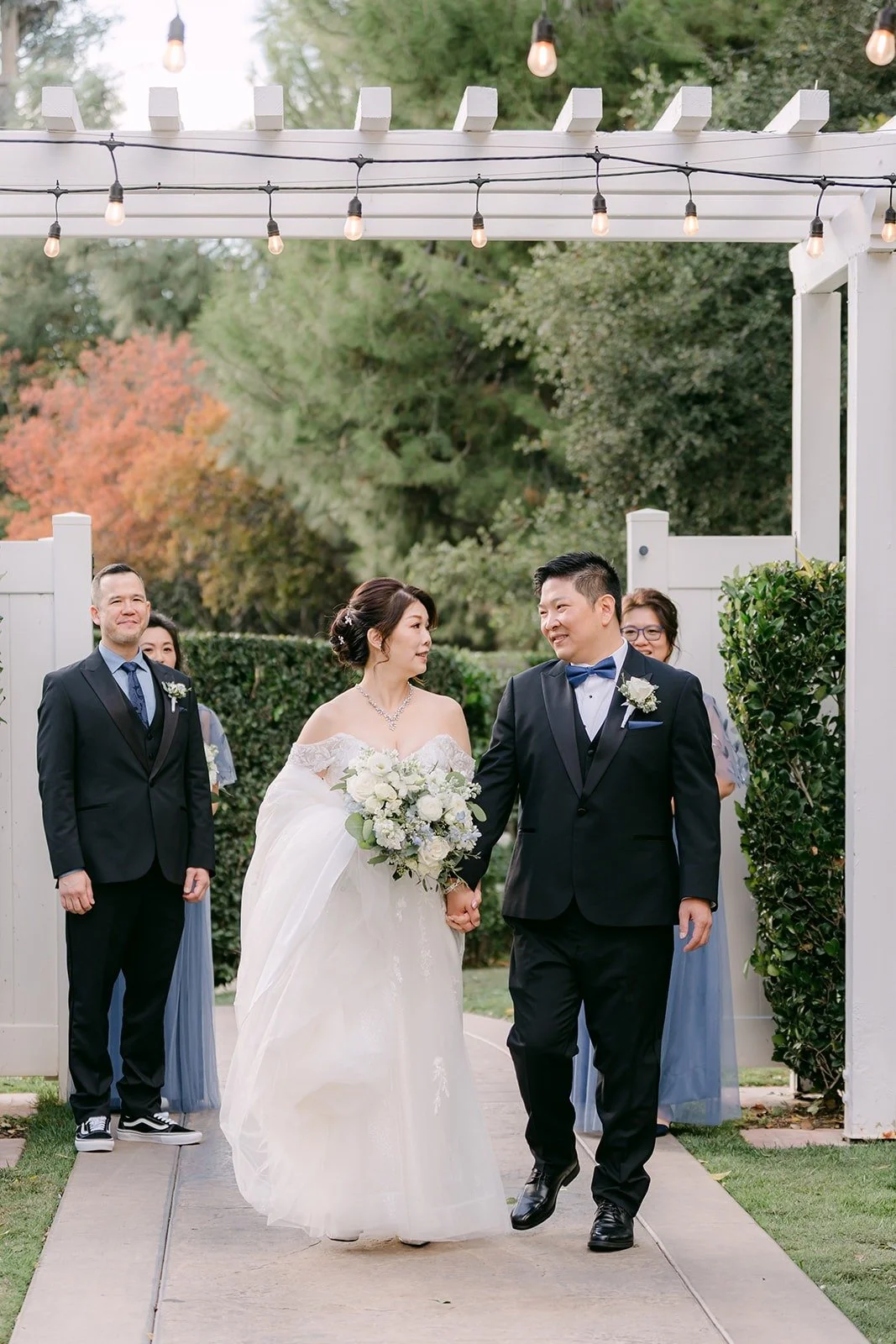 Sochi and Jay walking arm in arm with the wedding party behind them