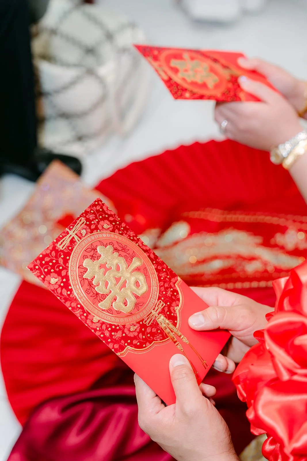 Red envelopes held in the bride's hands after the tea ceremony, photographed by One and Only Production.