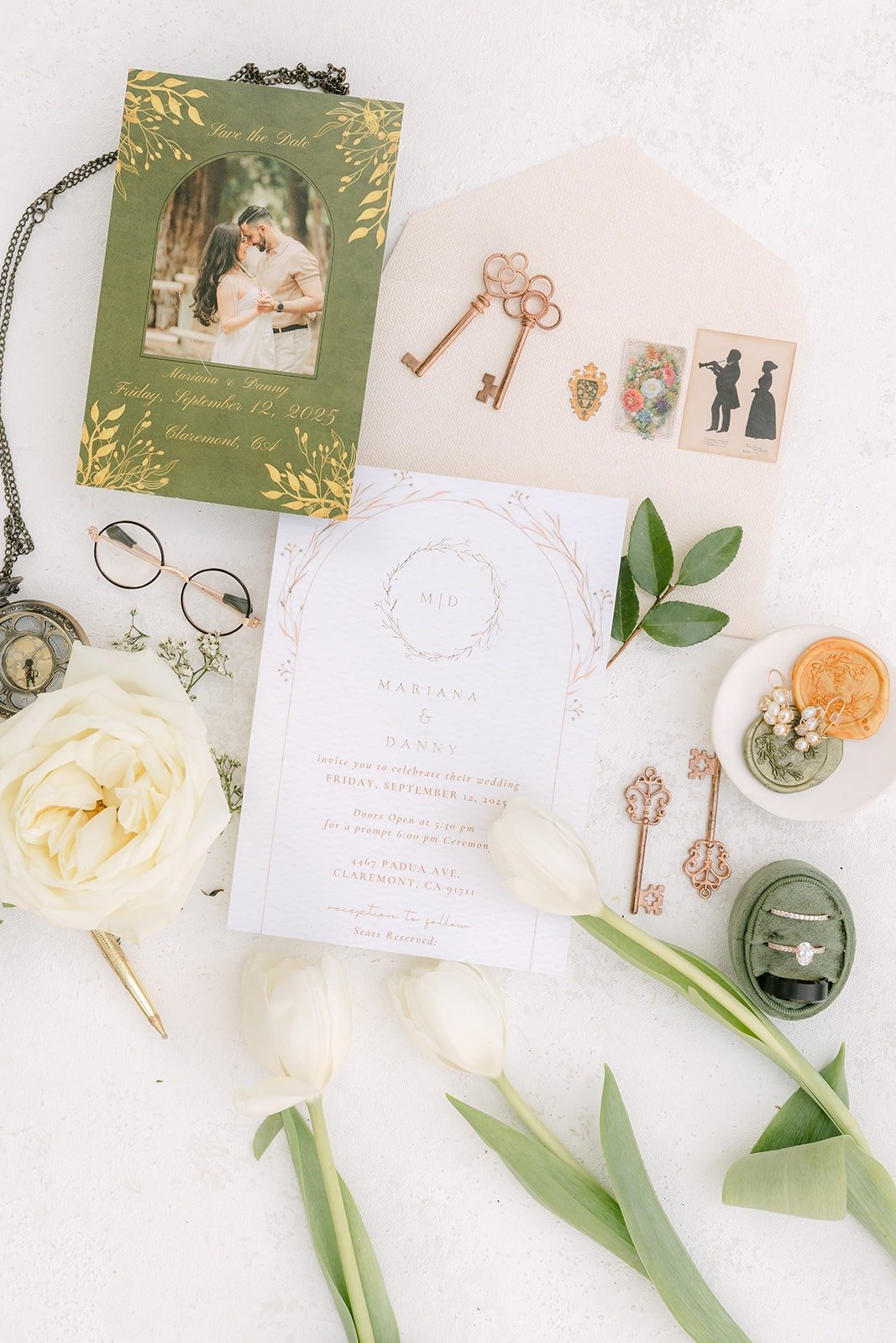 Mariana and Danny's flat lay with a green invitation, antique keys, wax seals and white roses