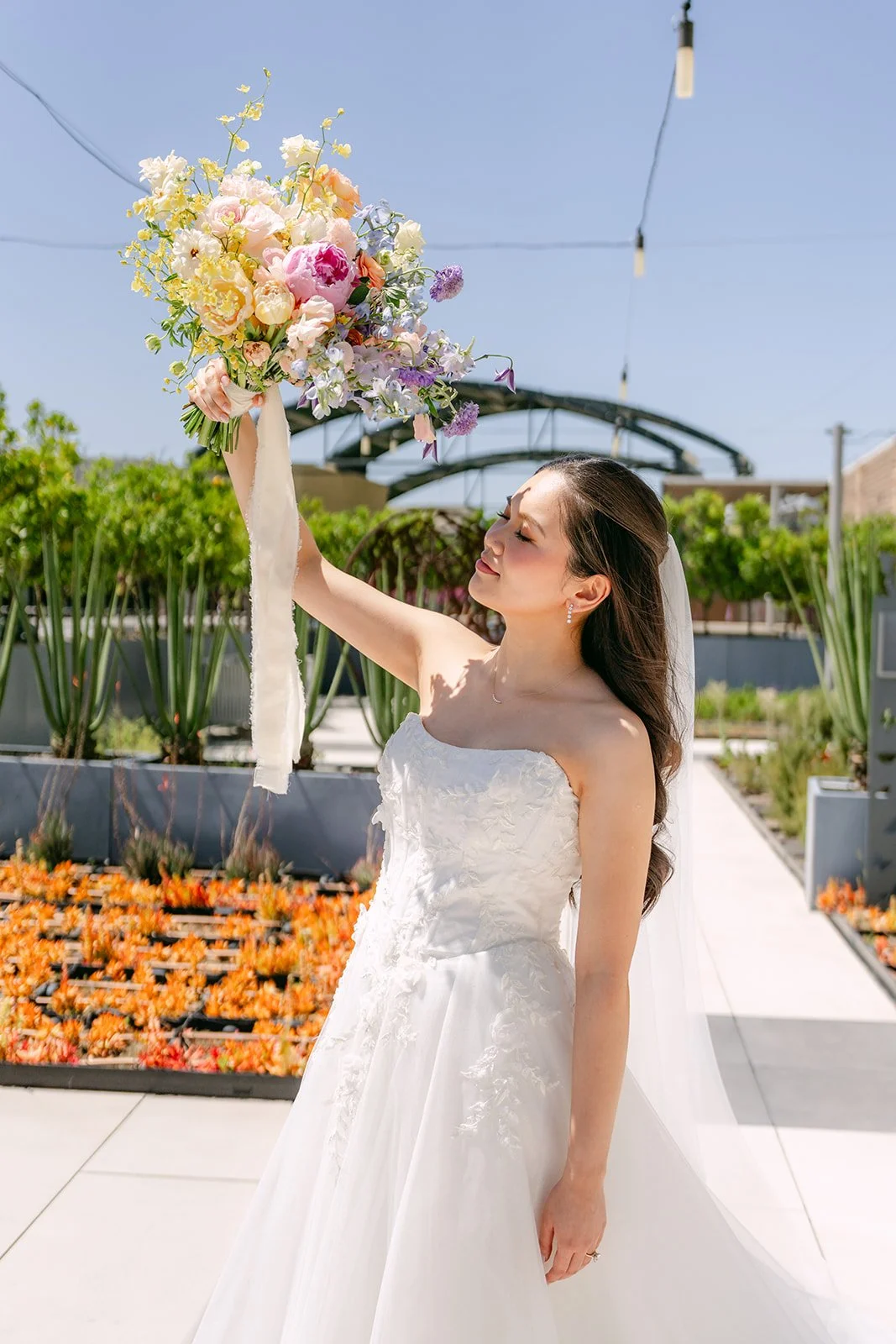 Bride raising her bouquet toward the sky on the garden terrace