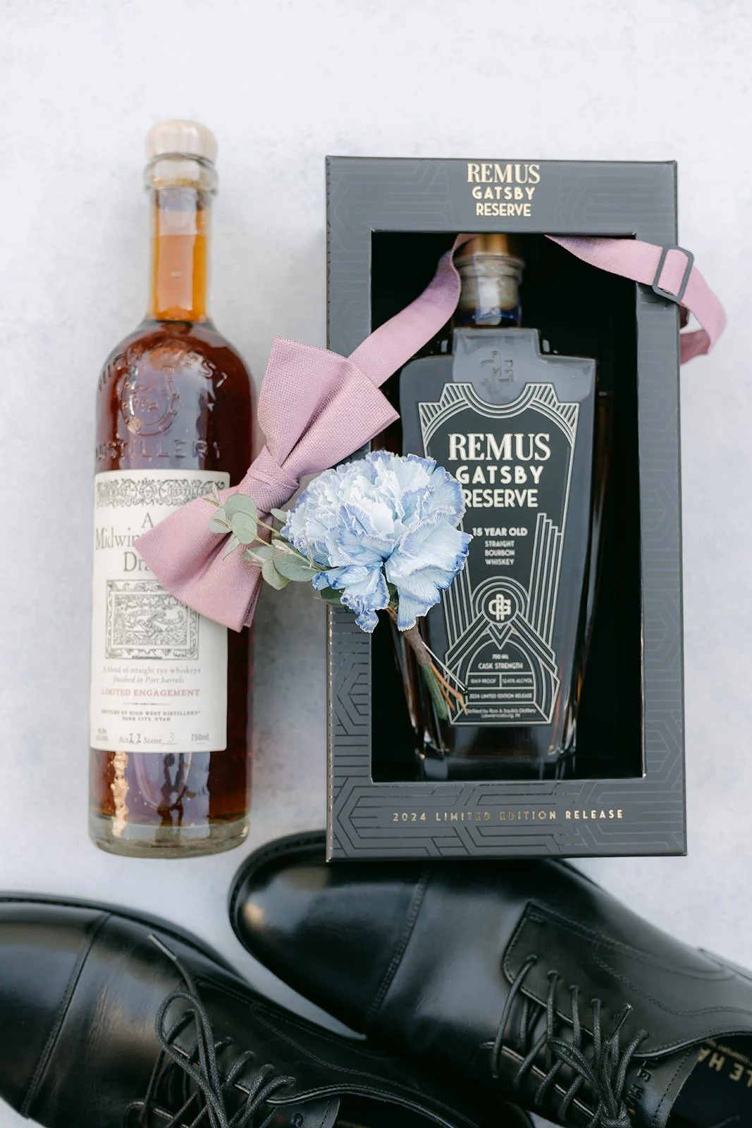 A bottle of whisky and a boxed decanter styled with Brandon's pink bow tie and boutonniere, photographed by One and Only Production
