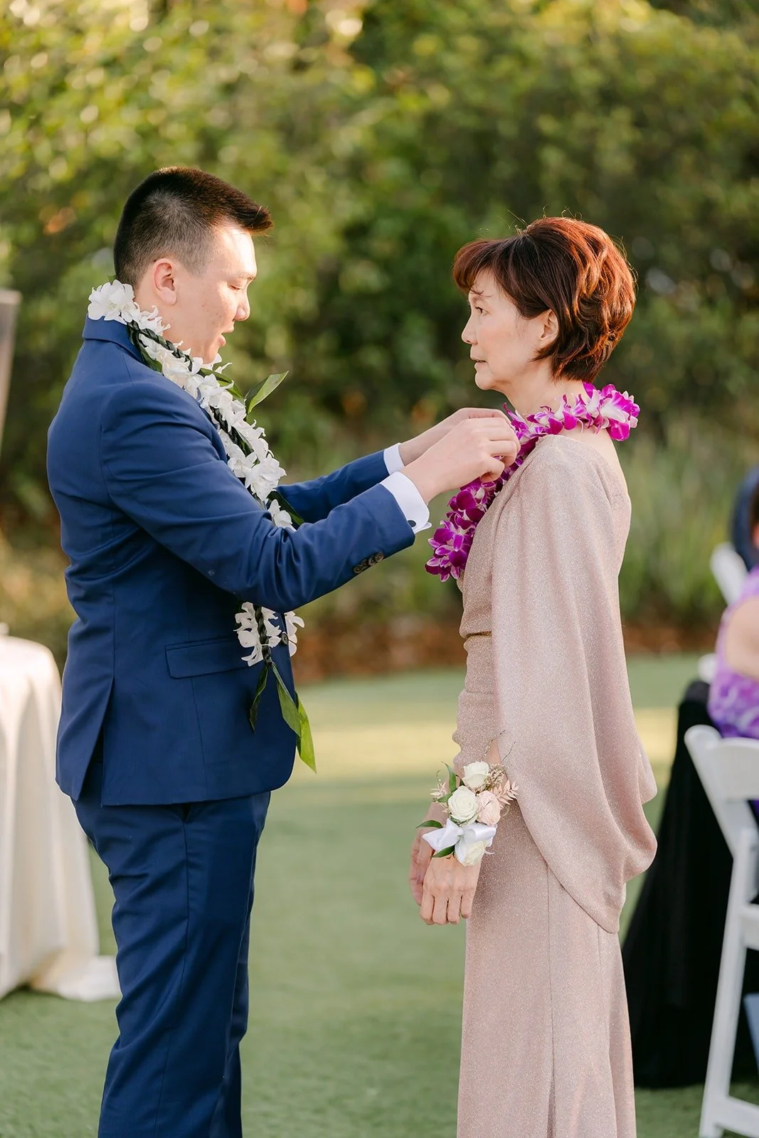 A family member placing a lei on Alex at the reception