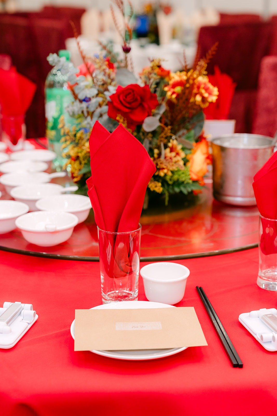 Rose centerpiece over a place setting with red napkins