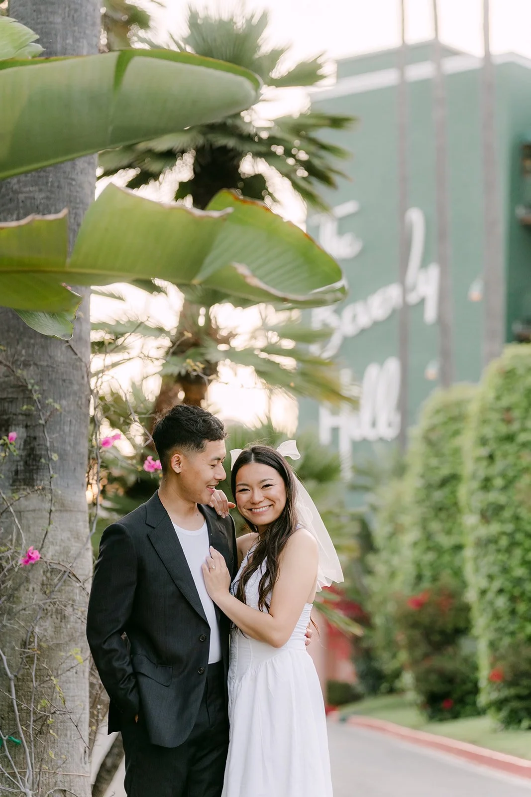 Jadee and Richard stand together beside a palm tree near the Beverly Hills Hotel.