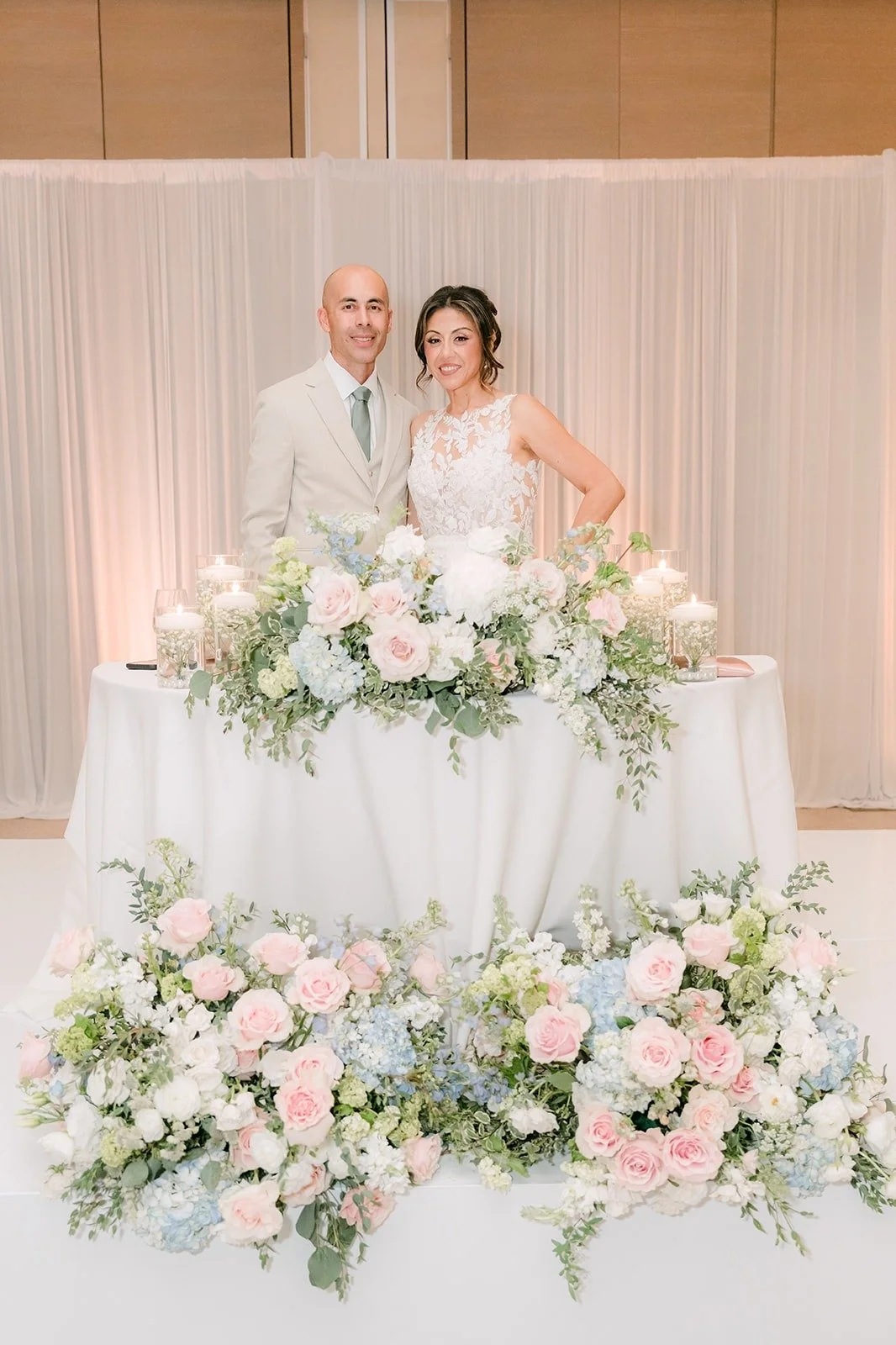 Francesca and Daniel at the sweetheart table framed by blush and white flowers