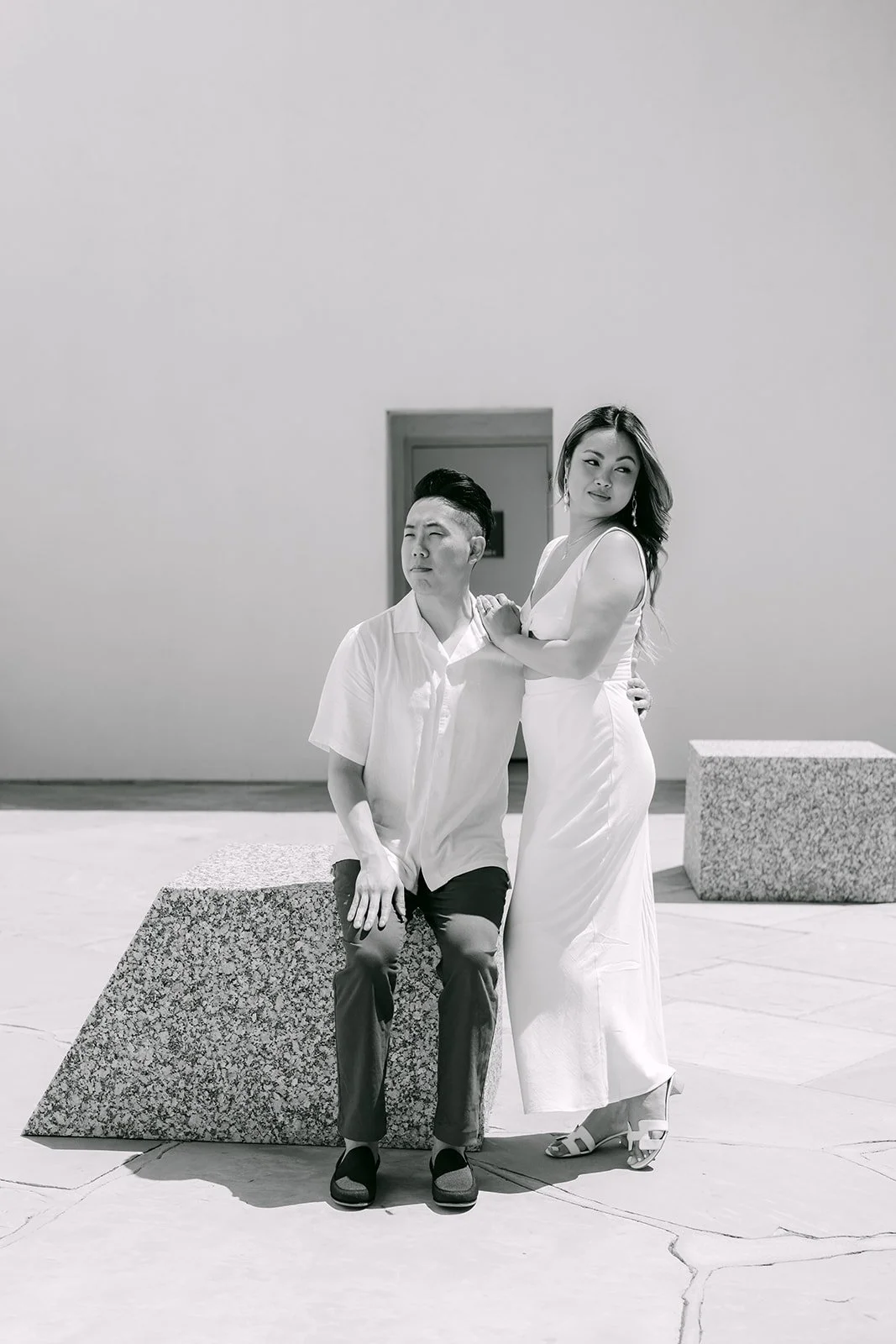 Black and white photo of Stephanie and Alan at a granite block against the white wall.