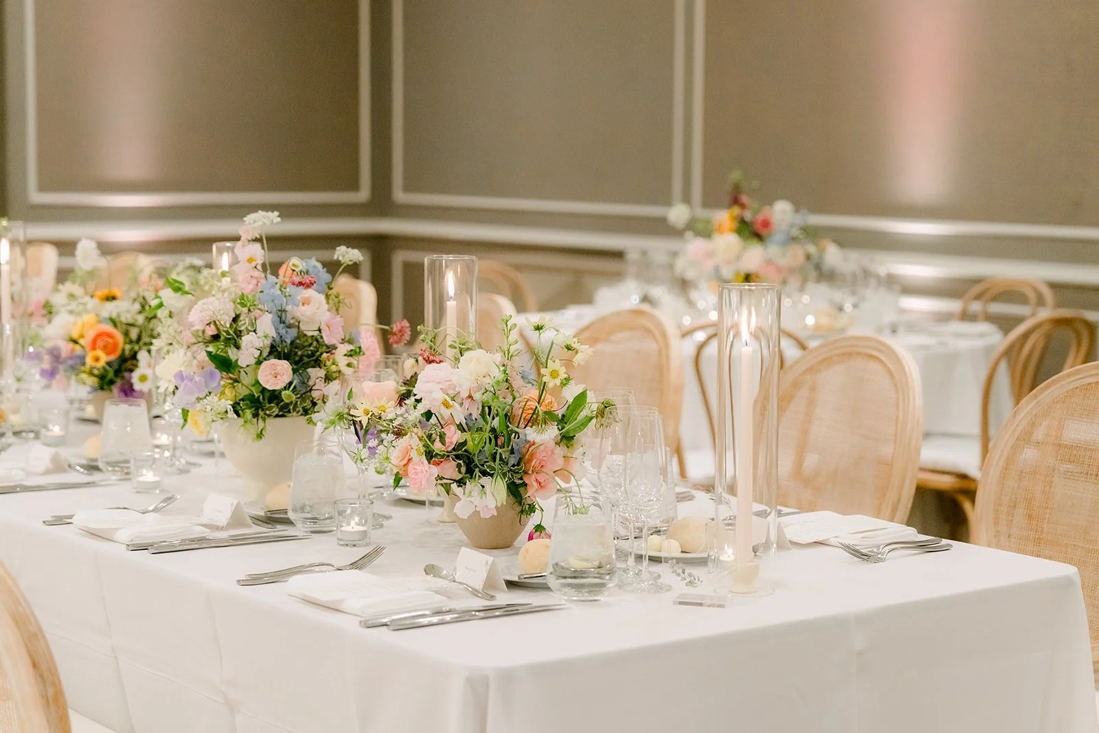 Long guest tables with white linens and low pastel florals