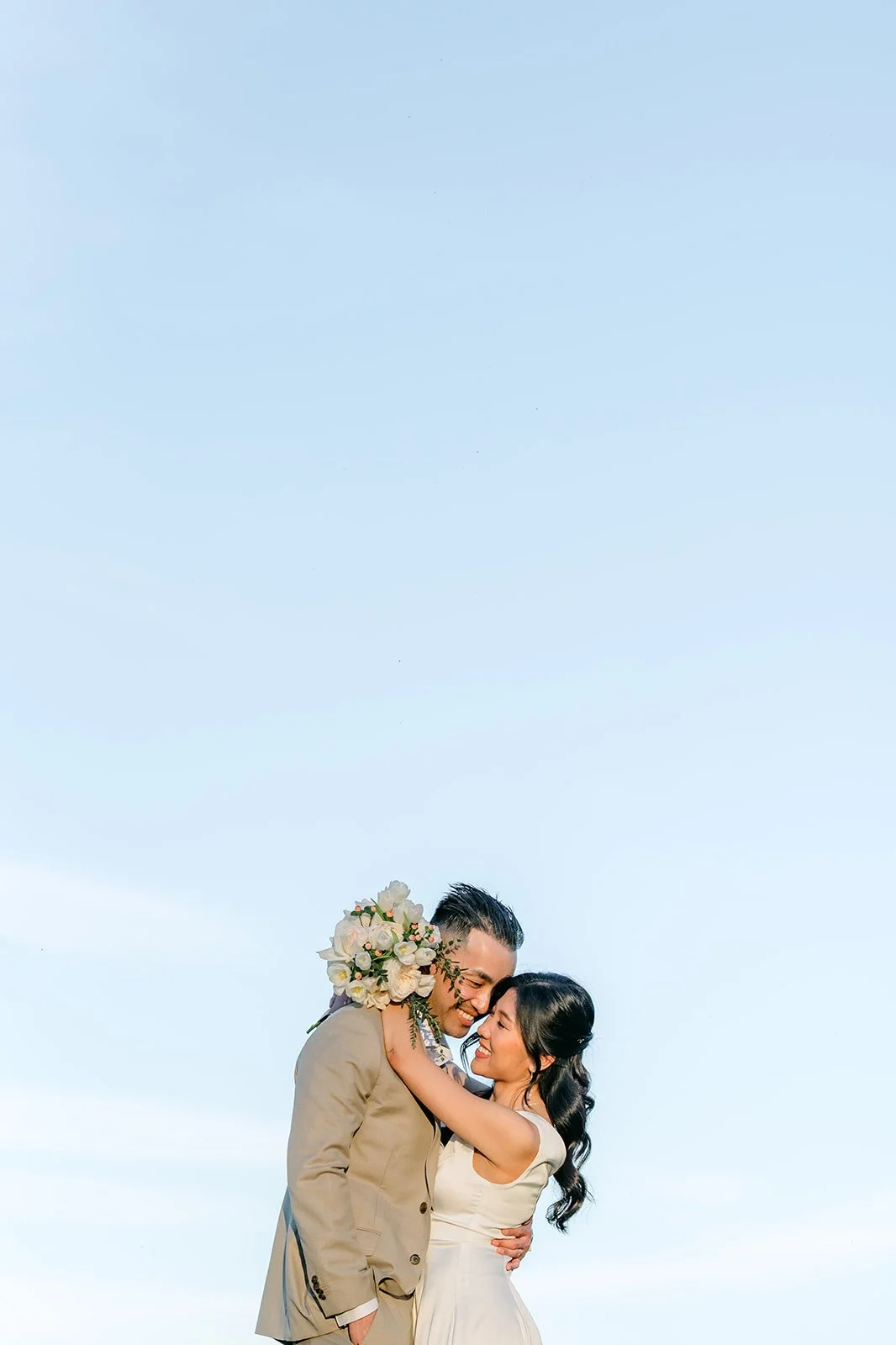 Kim and Vincent kissing against an open blue sky.