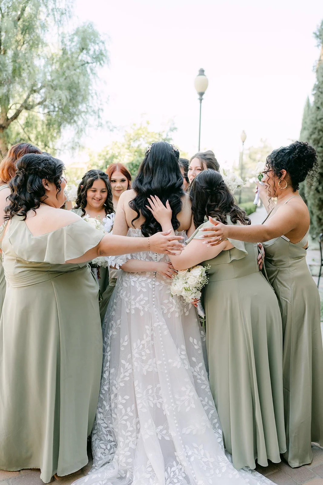 Fernanda's bridesmaids in sage green crowding around her.