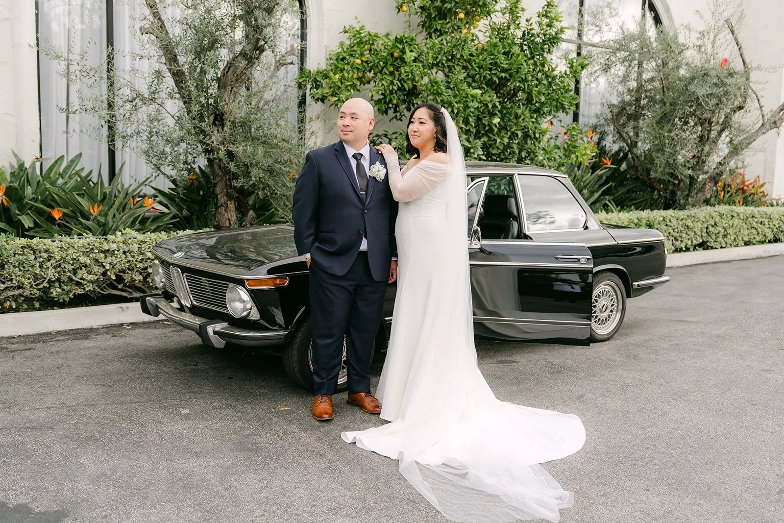 Vivian's long veil trailing behind her by the car