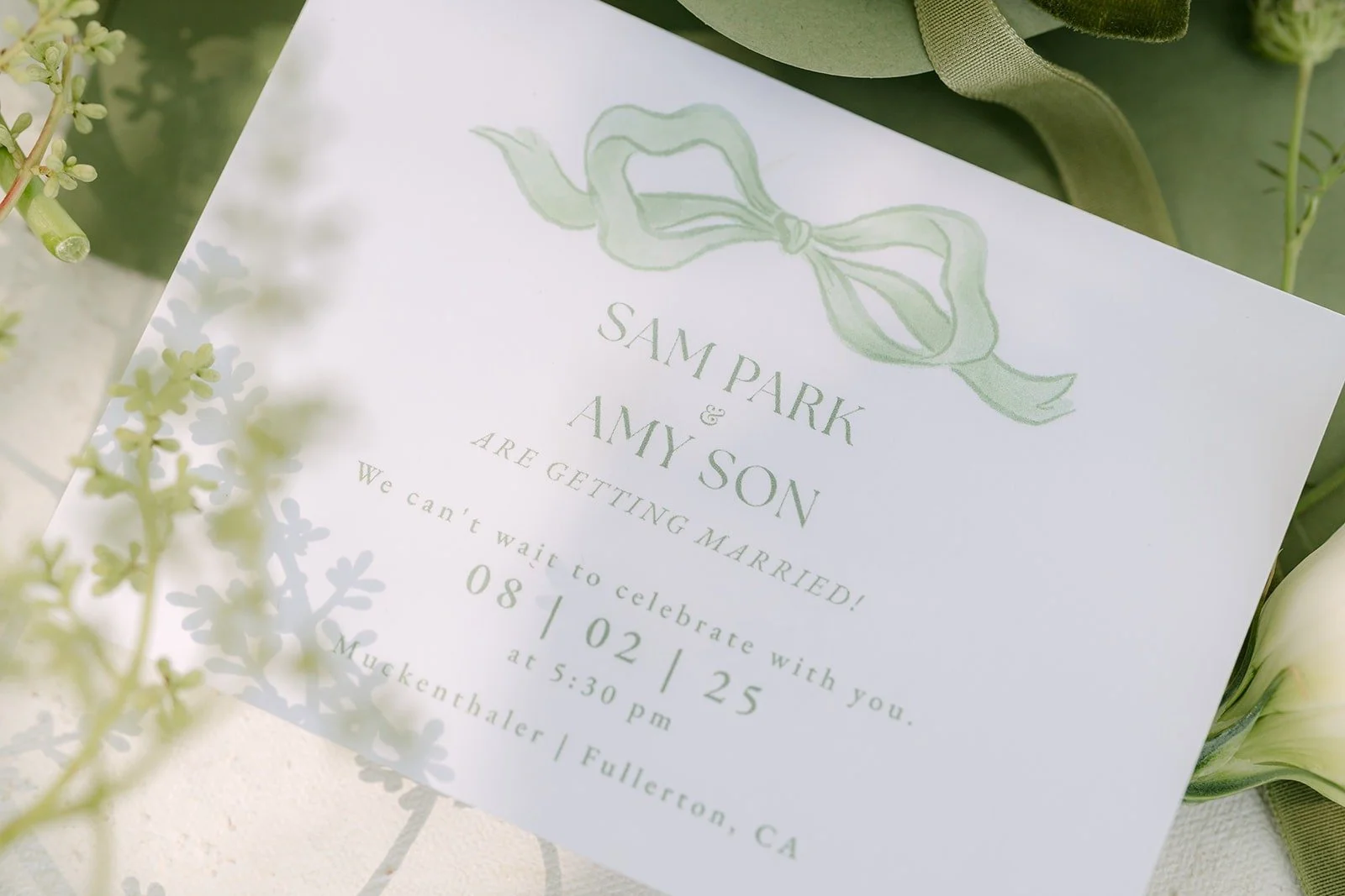 Close up of the invitation with a sage green ribbon motif