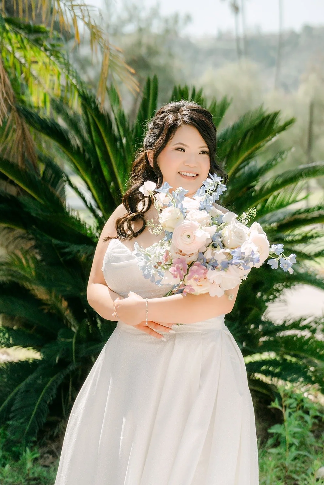 Florence smiling with her bouquet of blush and blue flowers