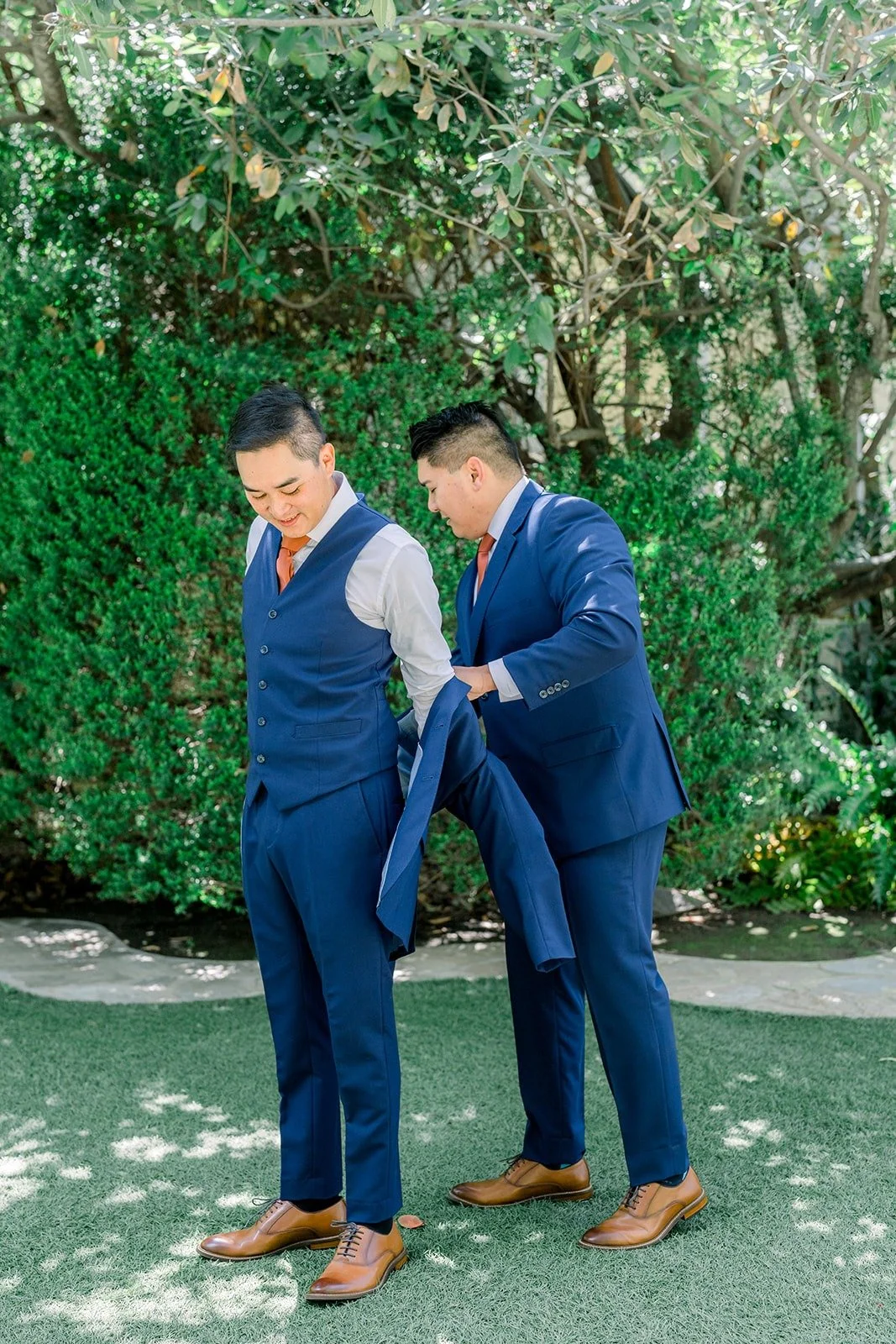 Vincent and a groomsman fixing a jacket on the lawn