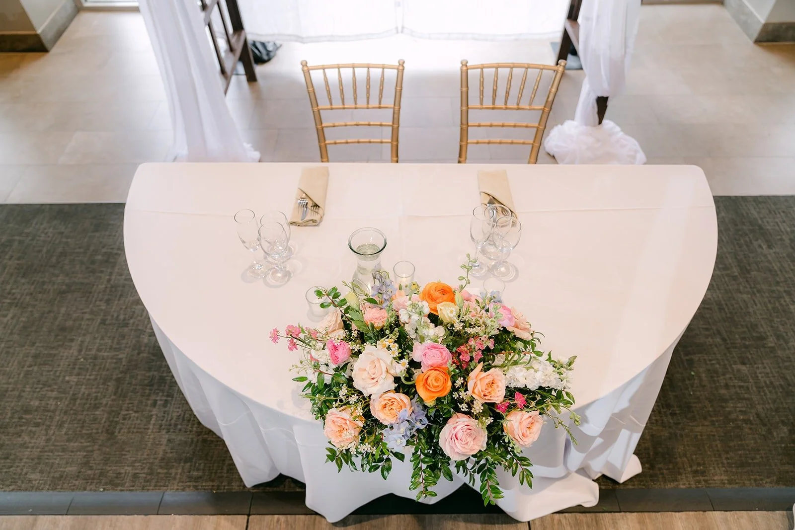 The sweetheart table with a peach and pink floral arrangement