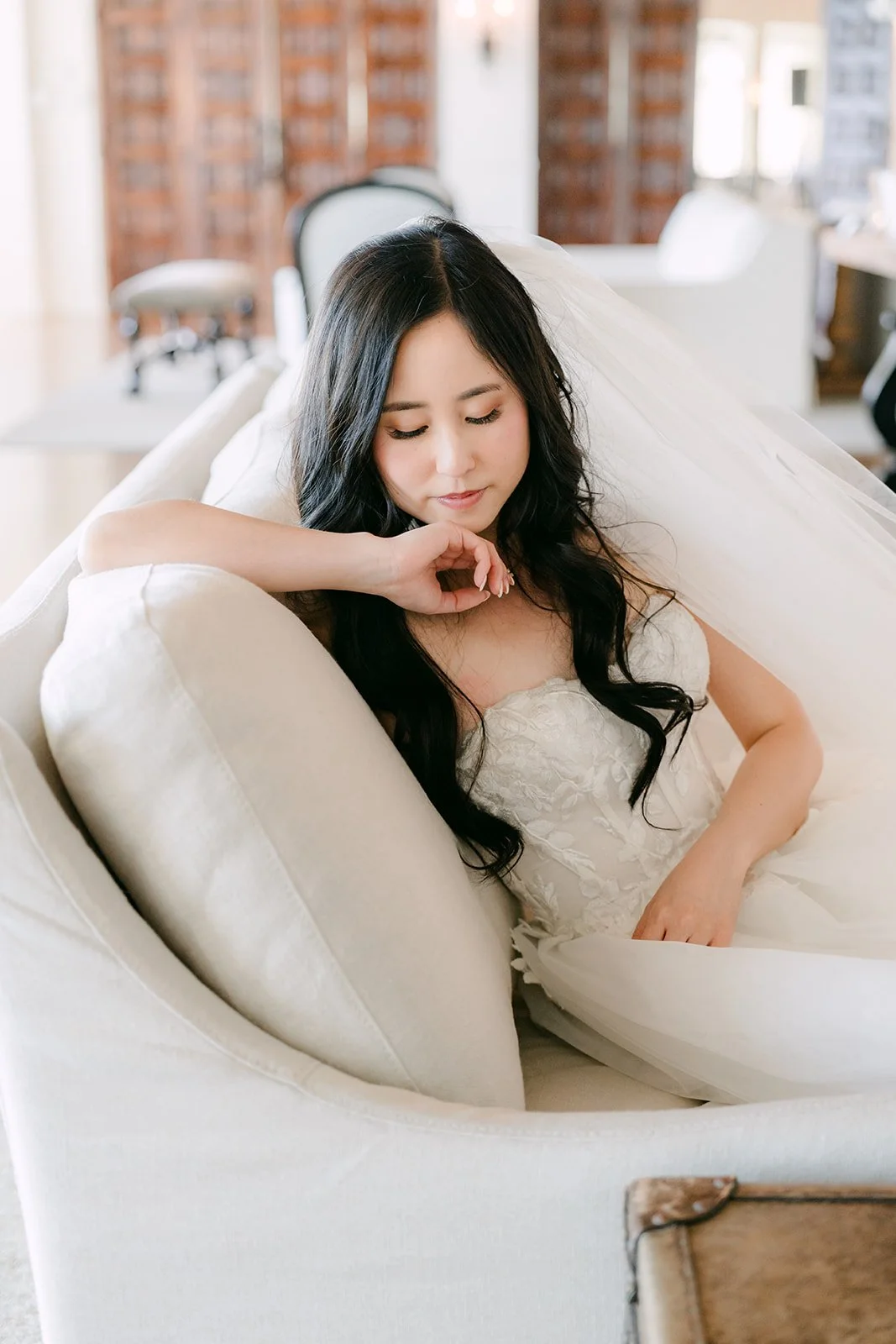 Bride relaxing on a white sofa in the bridal suite
