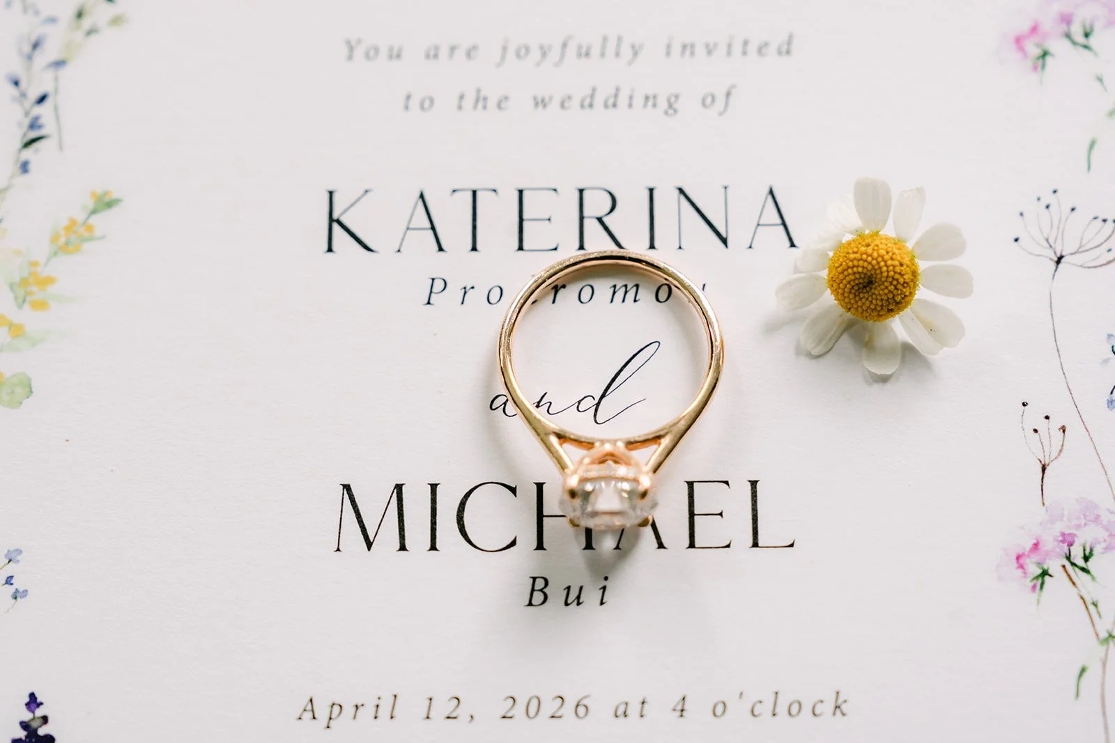 Wedding bands resting on Kat and Mike's floral wedding invitation