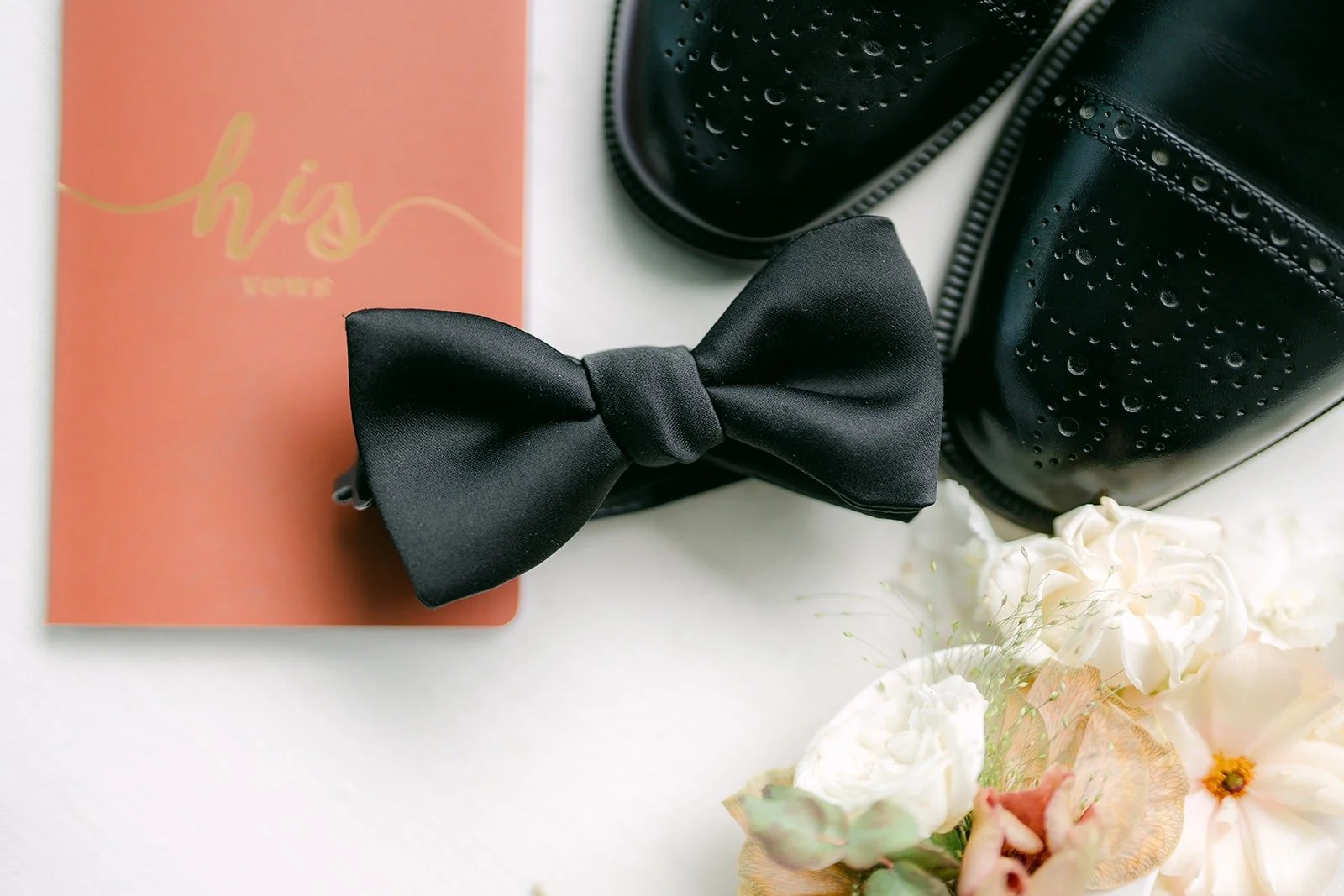Eli's black bow tie resting on a terracotta envelope, photographed by One and Only Production