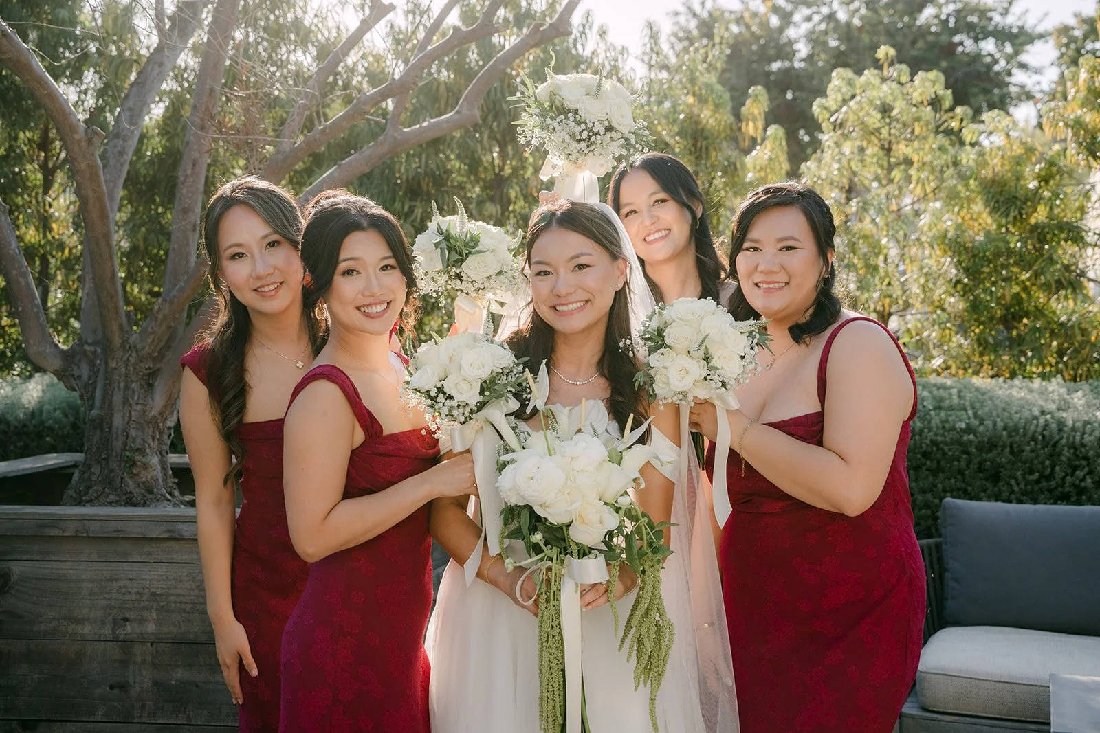 Jadee with her bridesmaids in burgundy holding white bouquets
