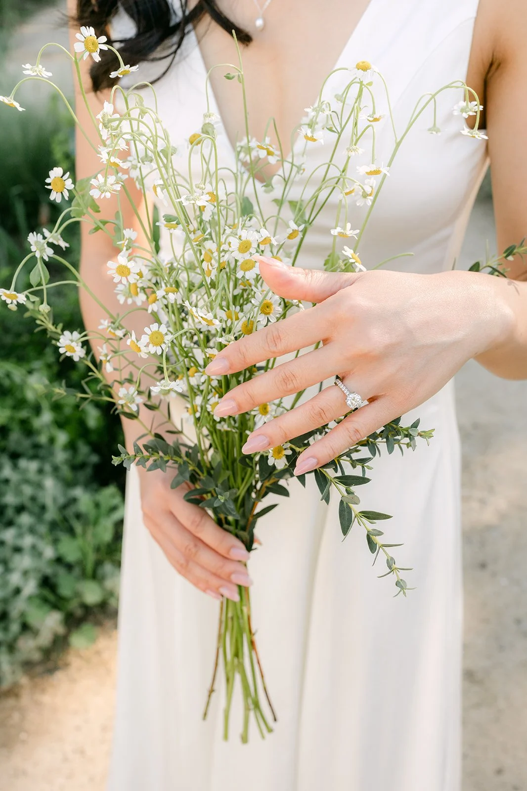 Kim's hands and engagement ring wrapped around her loose wildflower bouquet.