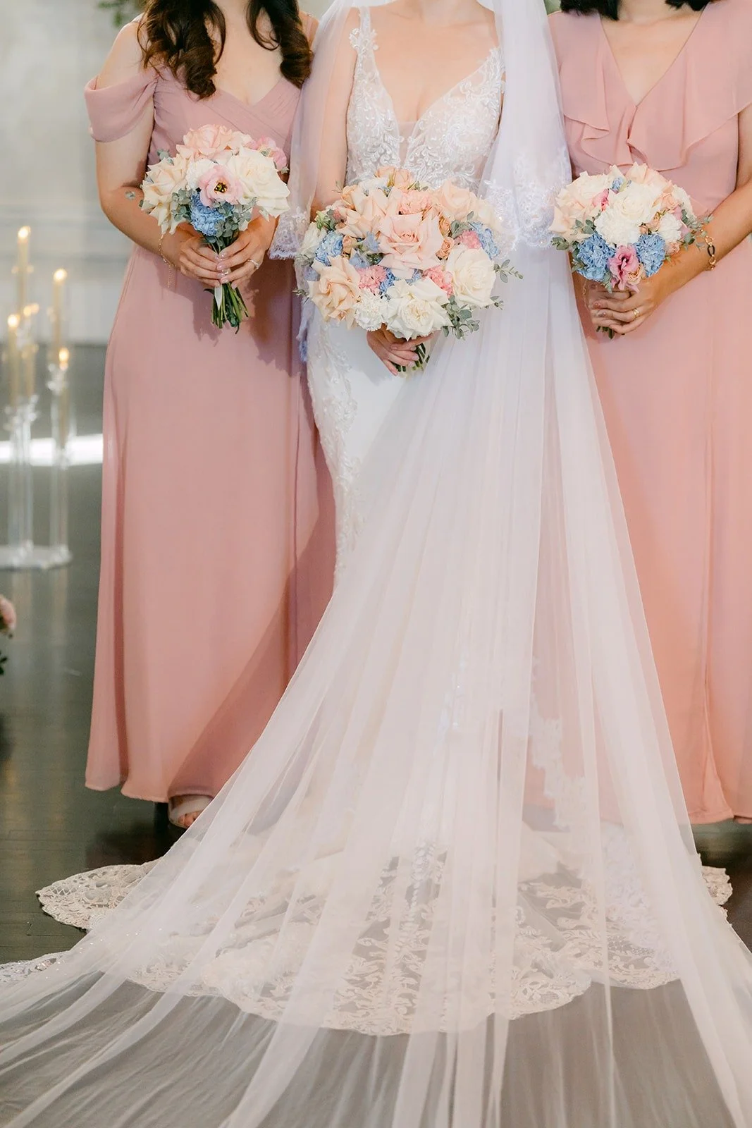 Elisa's gown and bouquet framed by her bridesmaids in blush pink dresses