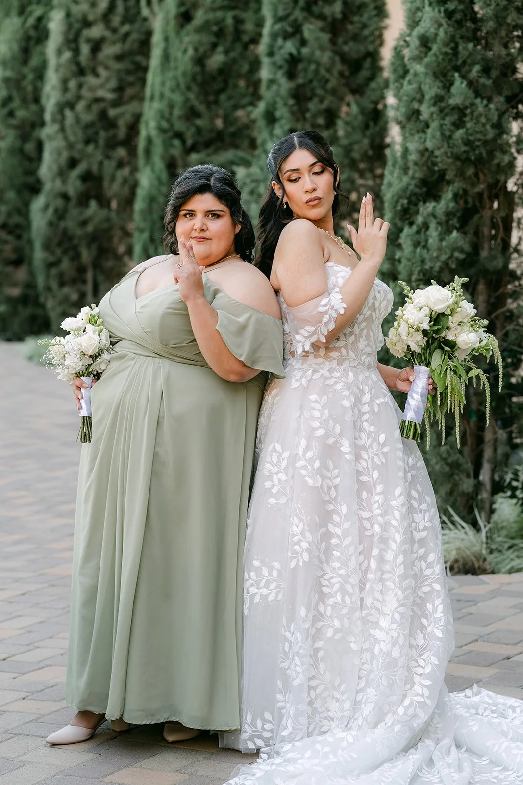 Fernanda with a bridesmaid in sage holding her bouquet.